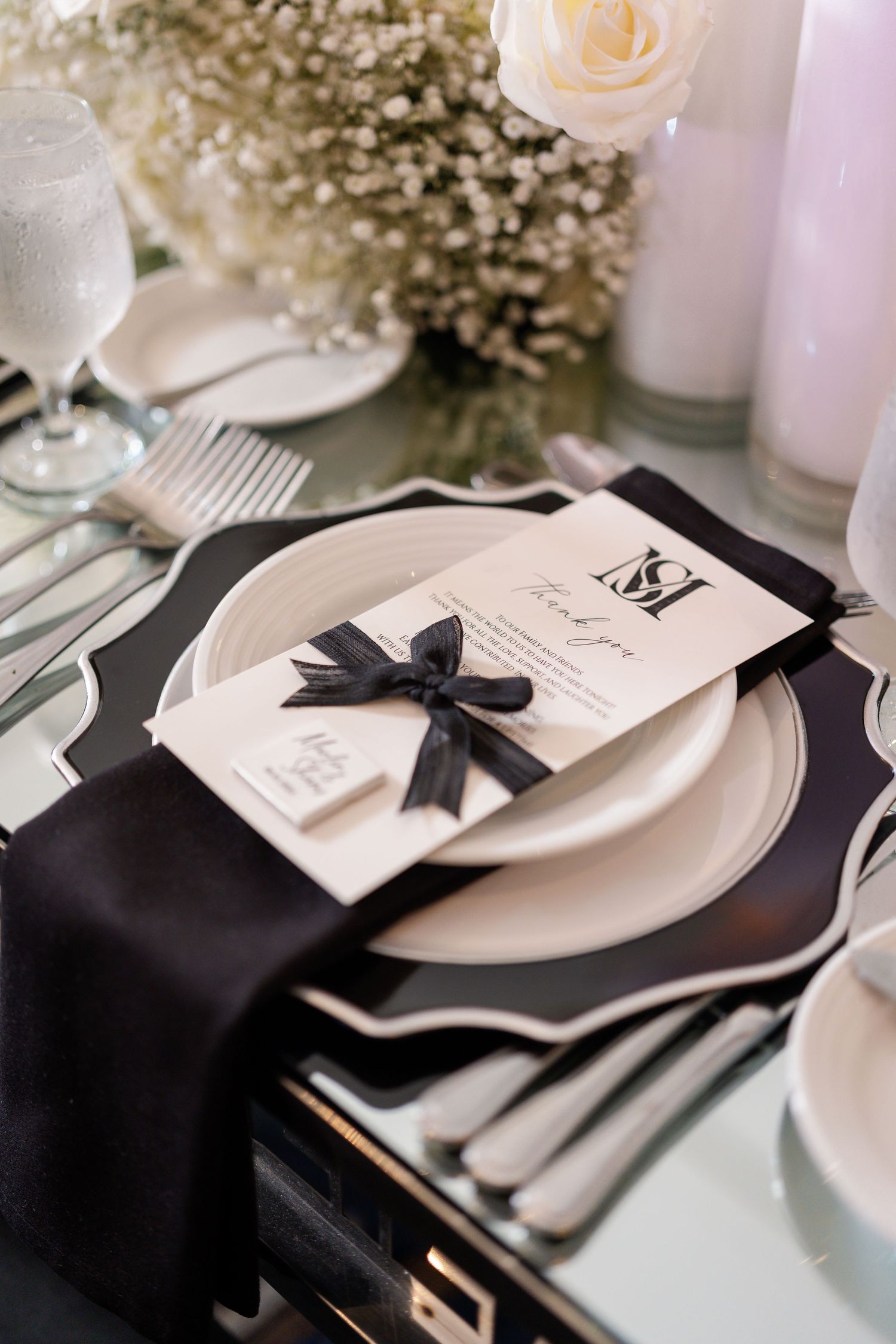 Elegant black and white place settings with ribbon-tied menus and delicate floral accents.