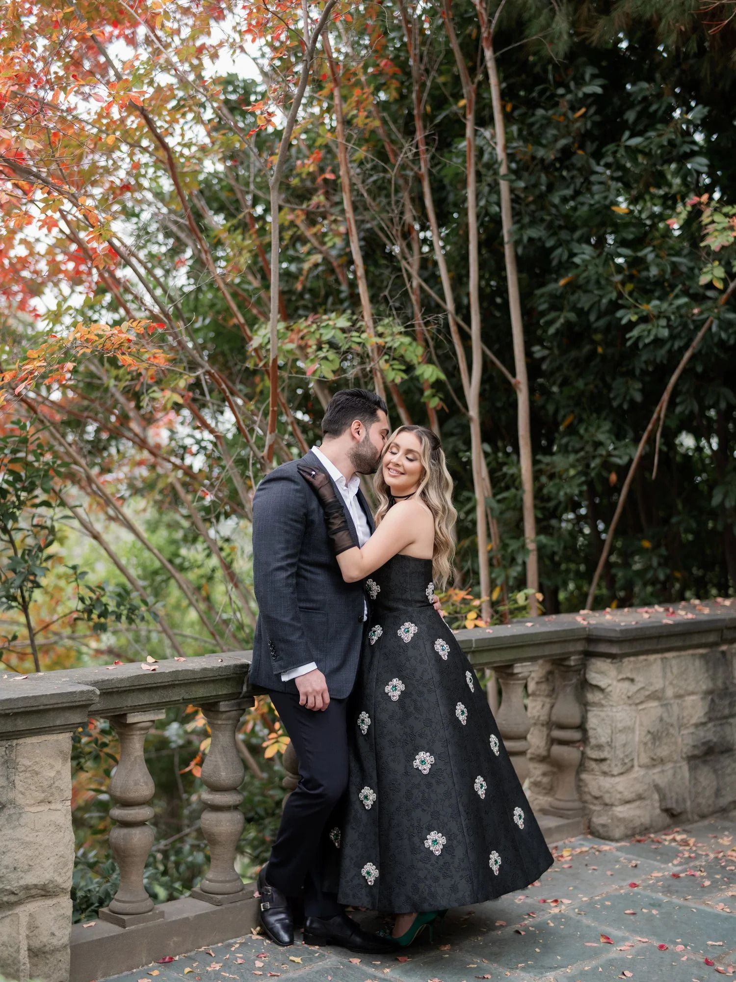 A romantic moment on stone balustrade surrounded by autumn foliage.