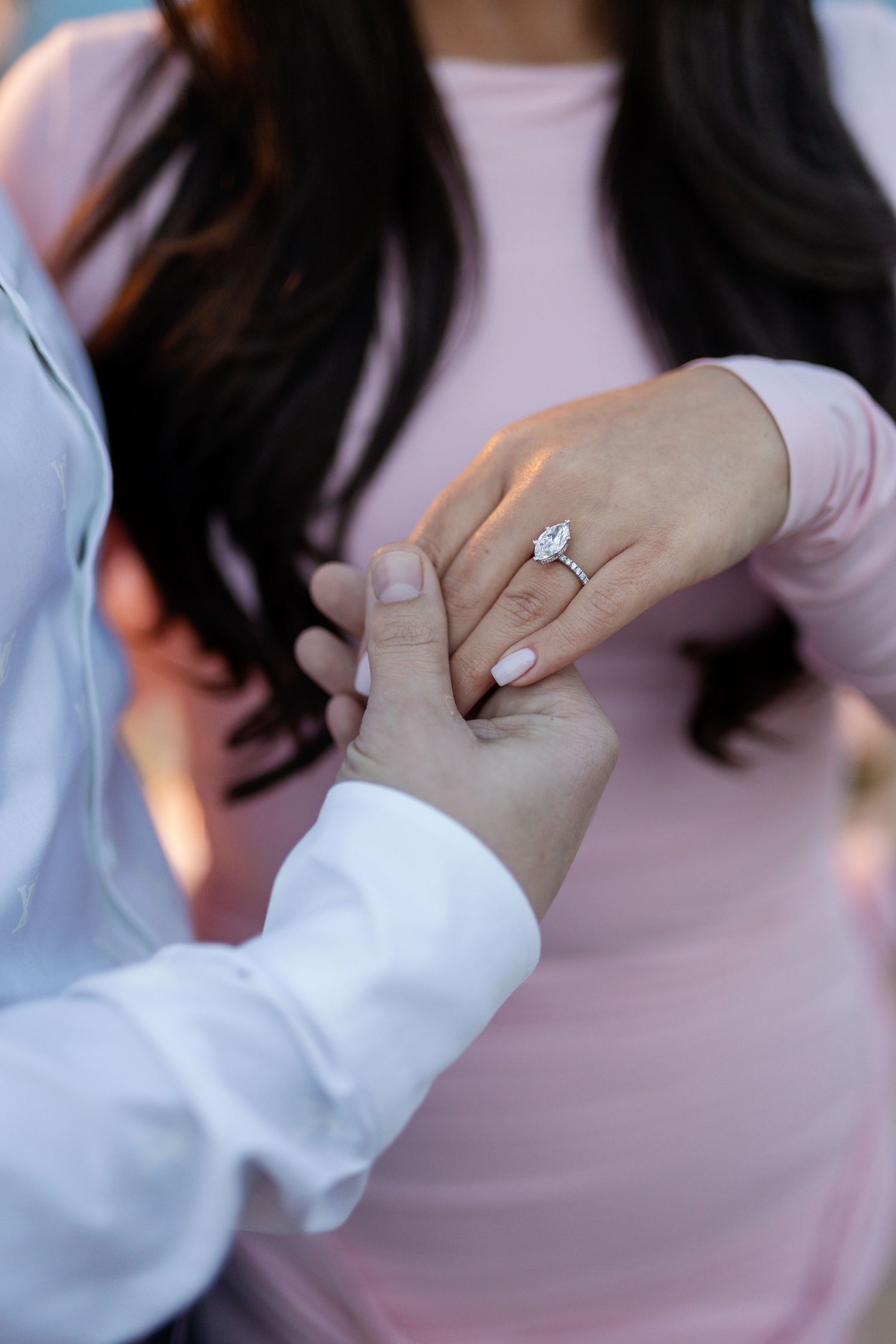 Close-up of engagement ring being placed on hand during romantic waterfront proposal.