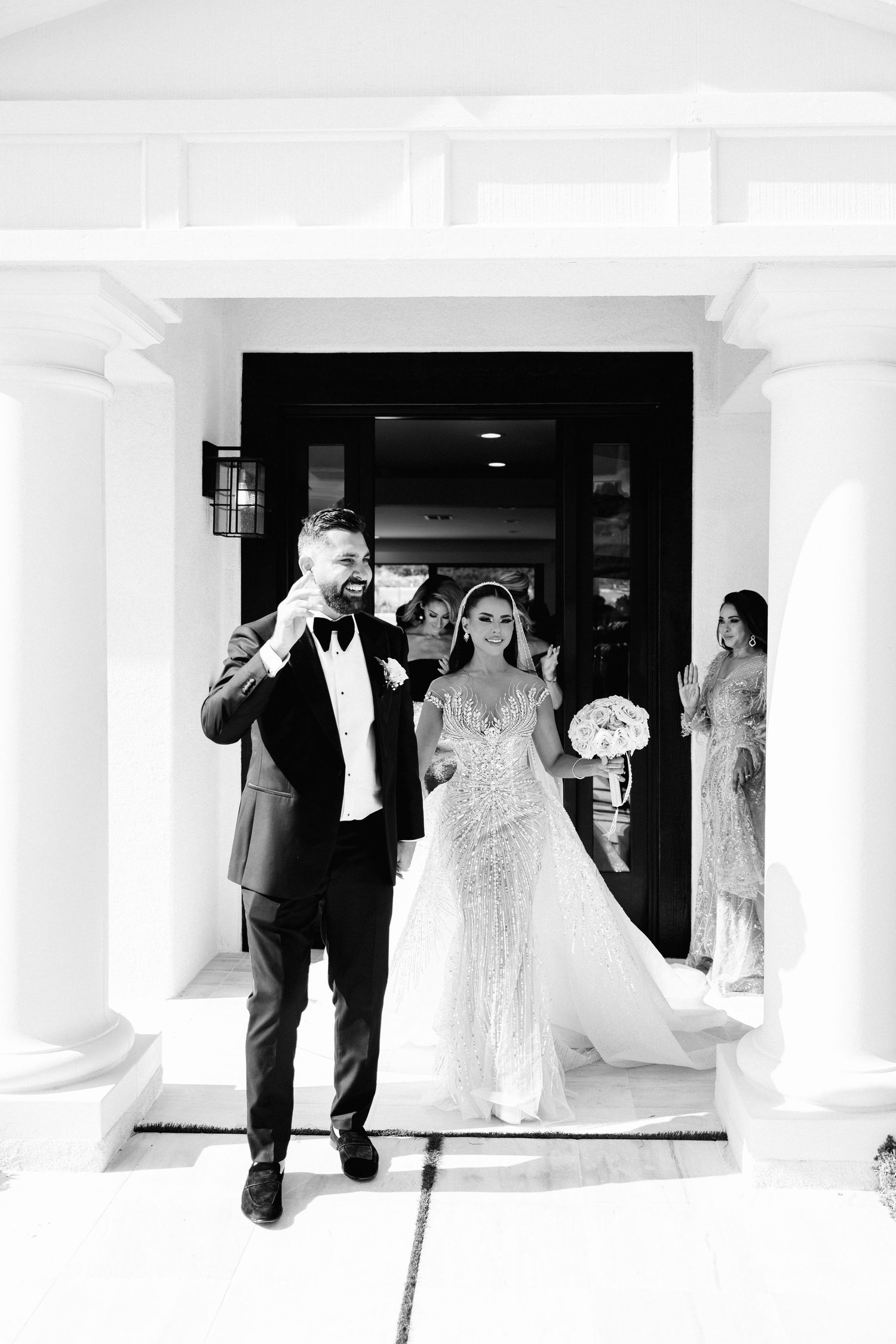 Black and white wedding photo sequence showing couple walking through venue hallway.