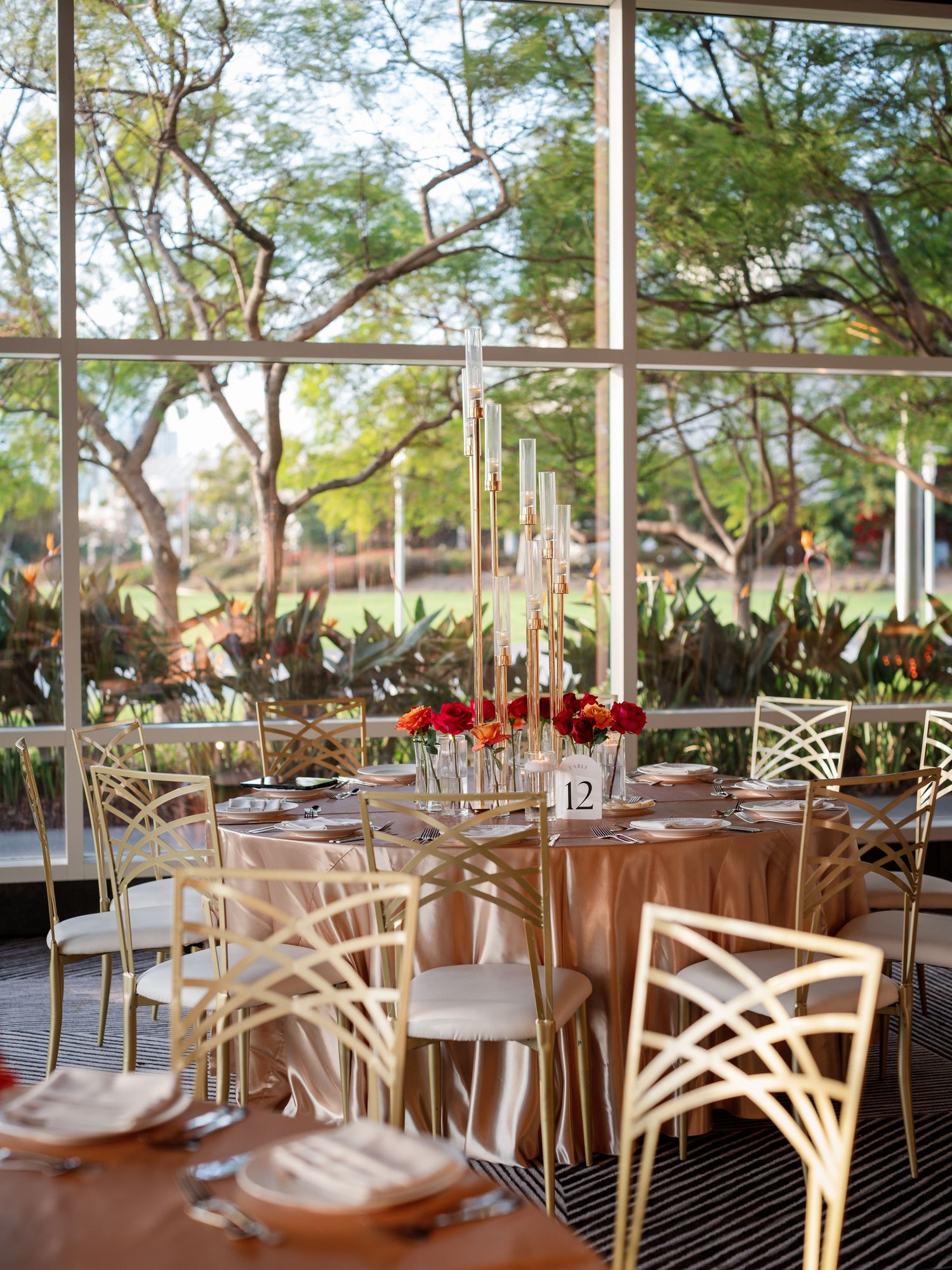 Modern wedding reception venue with crossback chairs and elegant table settings beneath large windows.