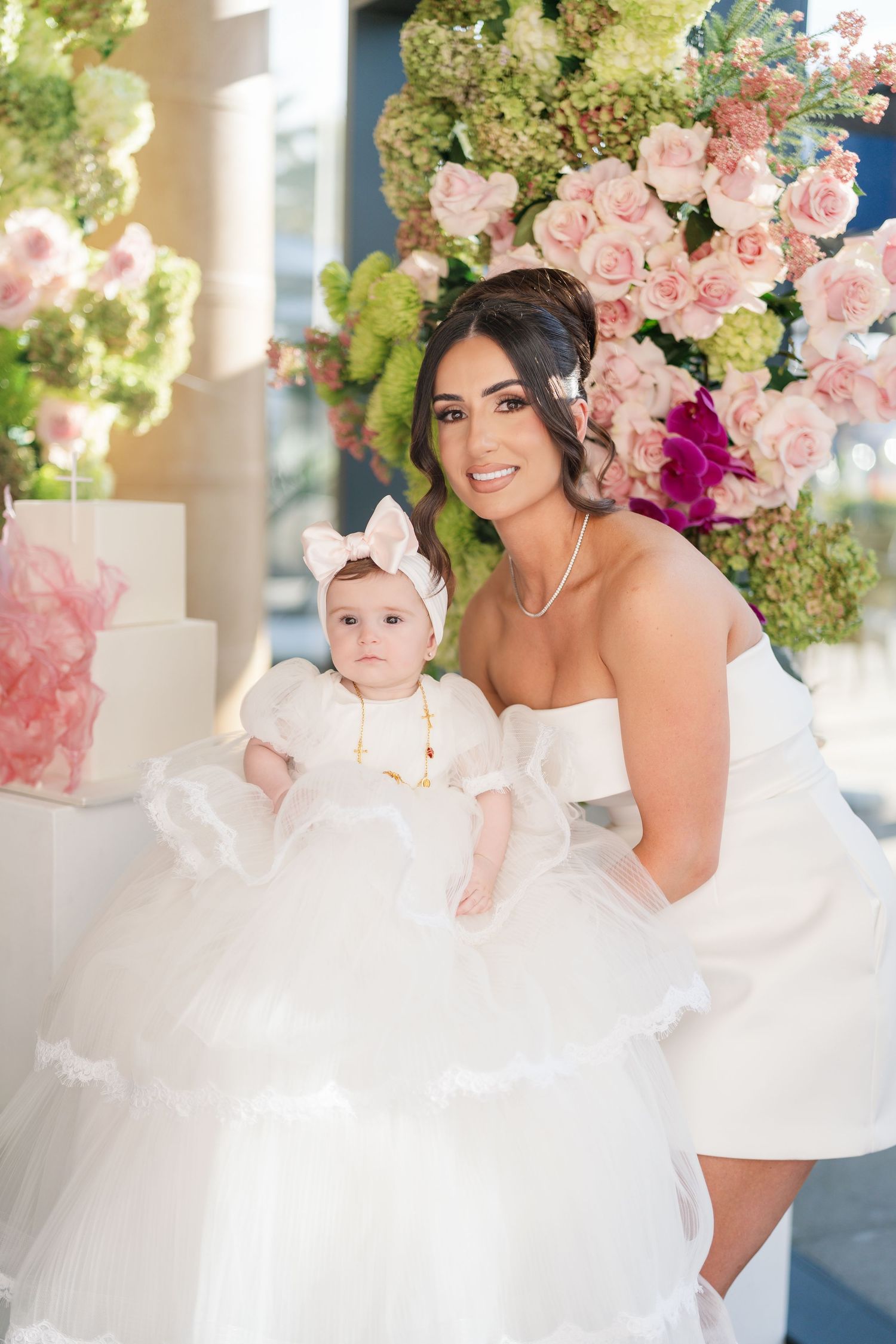 Beautiful white wedding scene with elegant floral arrangements of pink roses and hydrangeas decorating the background.