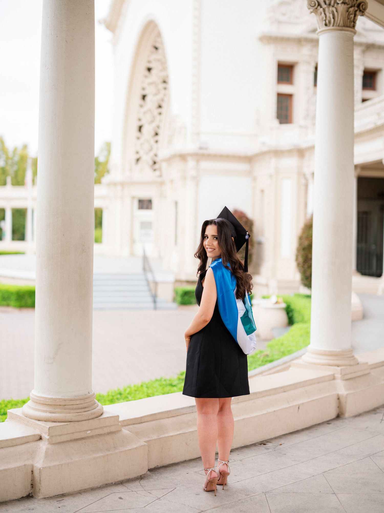 Graduation photos showcasing a graduate walking along a colonnade with classical architecture.