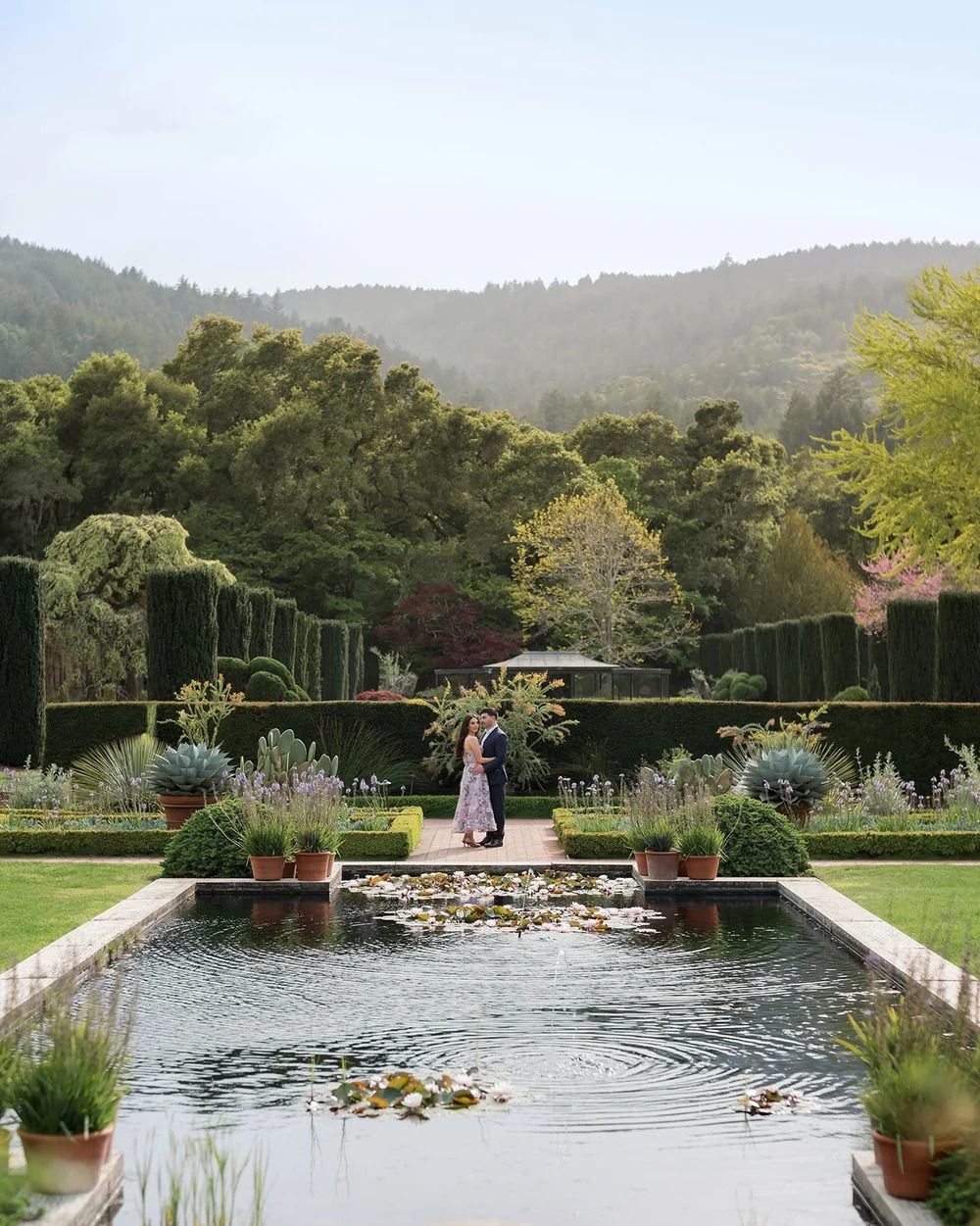 A serene reflecting pool surrounded by manicured gardens and mountain views.