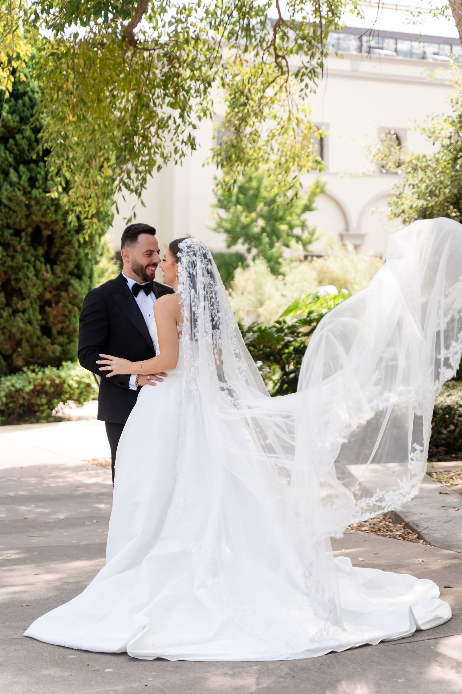 A beautiful wedding photo featuring a flowing veil and white gown against a garden backdrop.