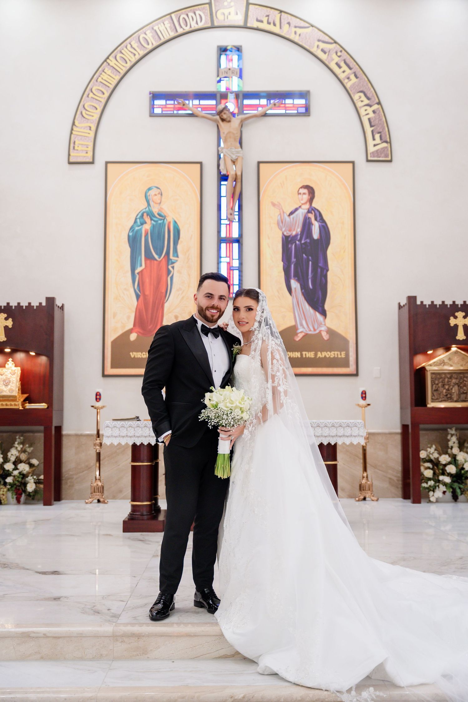 Wedding ceremony in a church with religious artwork and floral decorations.