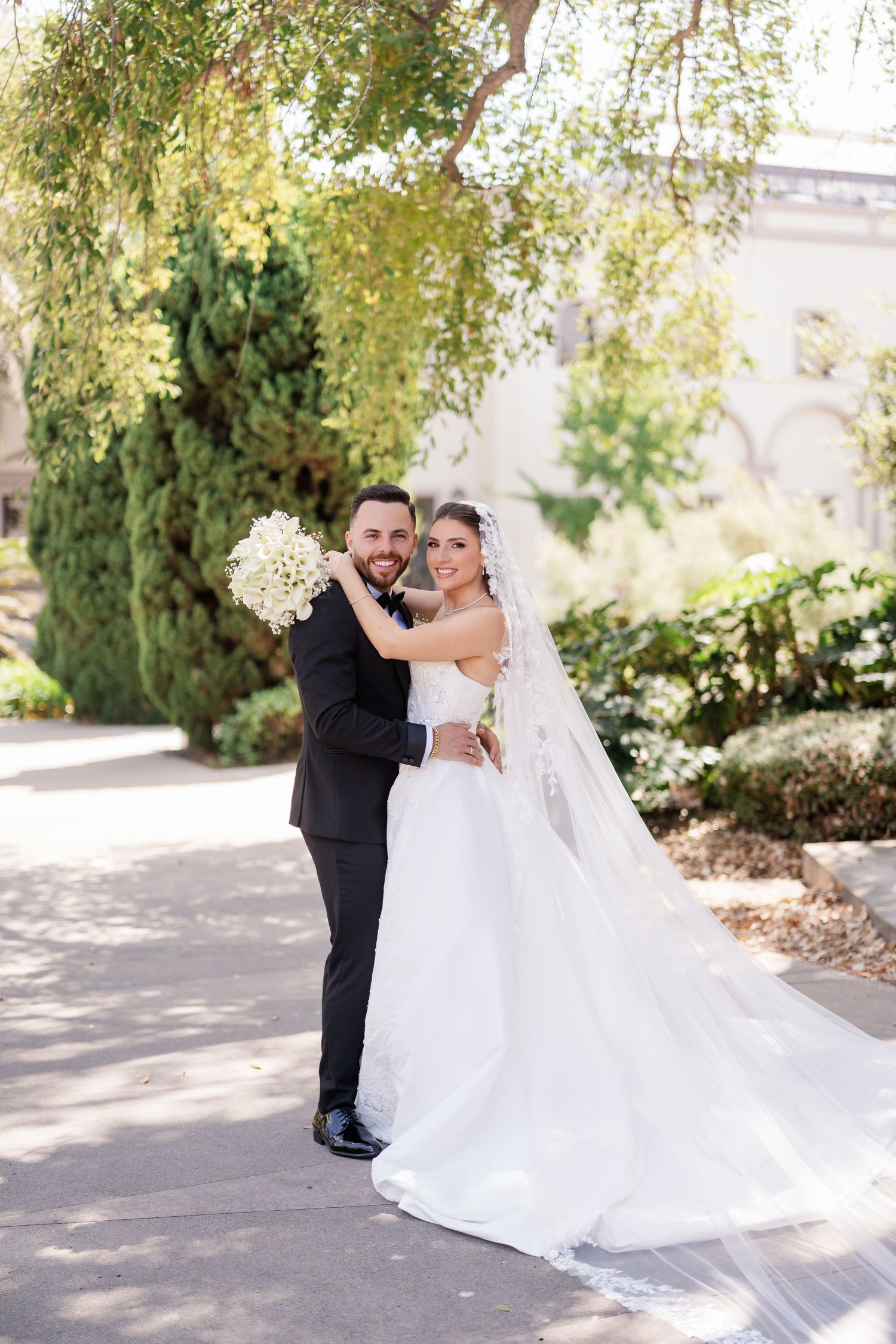 A joyful wedding moment captured in a garden with the bride holding a white bouquet.