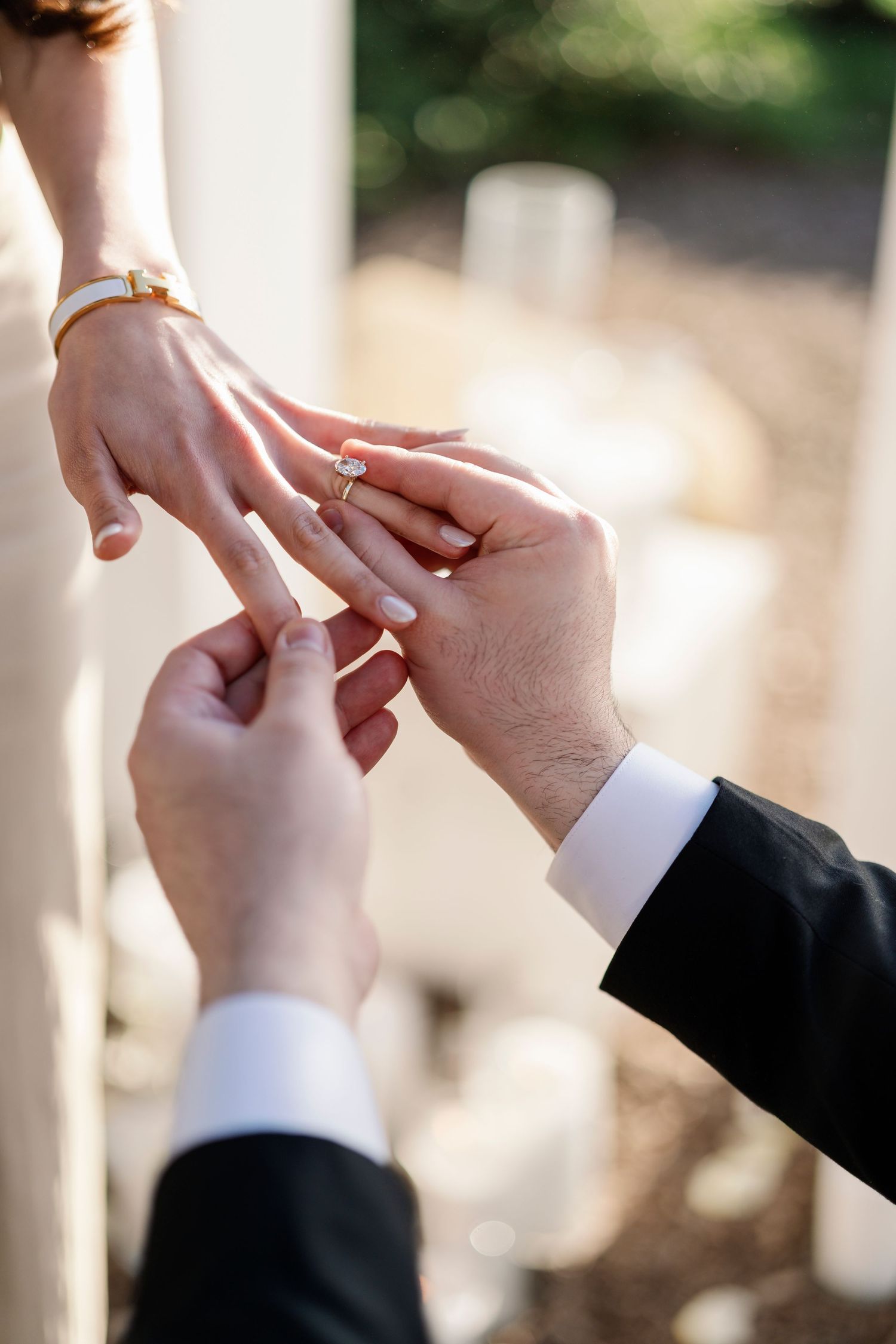 Close-up of hands exchanging rings during an intimate outdoor ceremony.