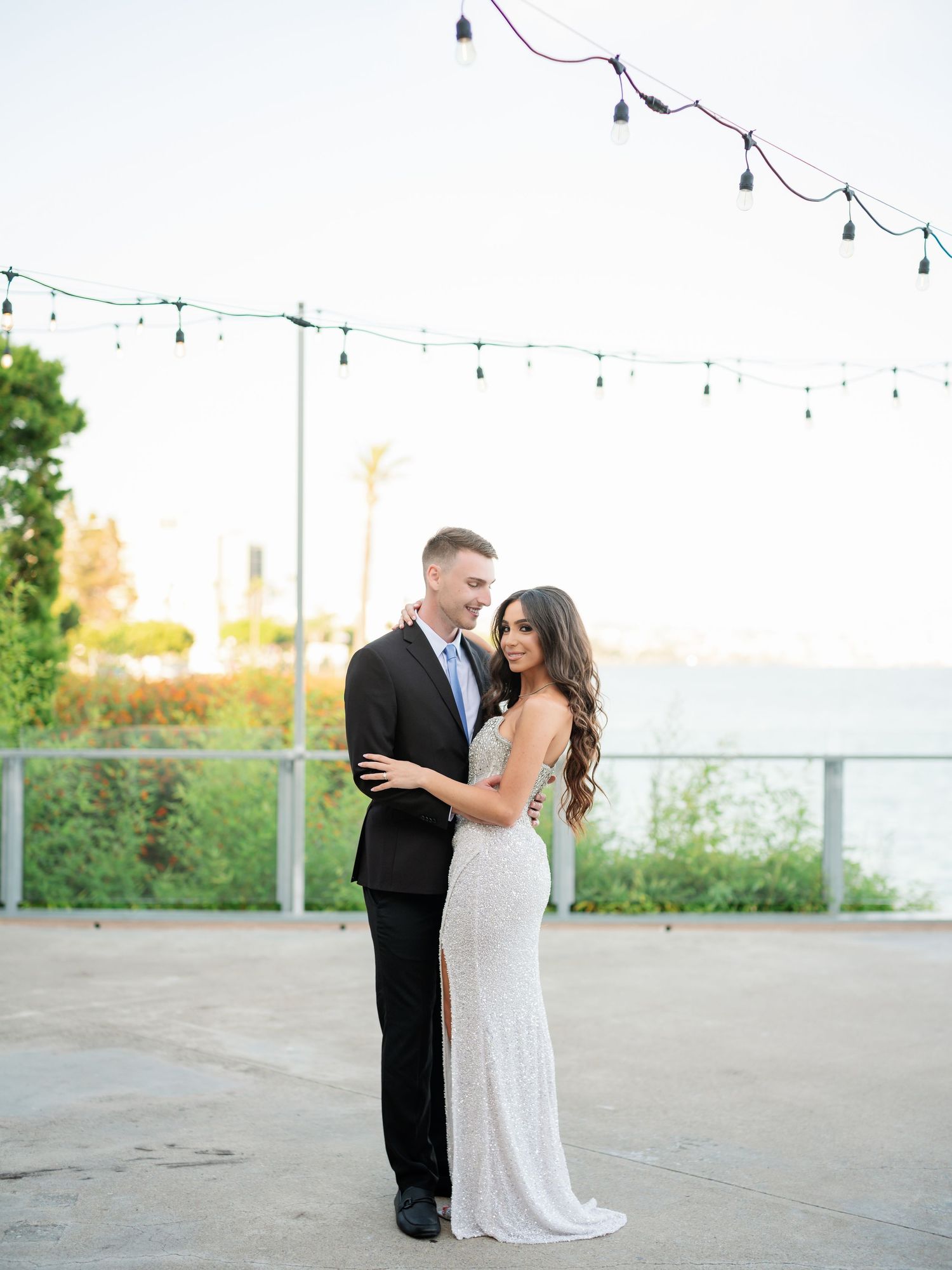 Couple shares romantic moments under string lights at an outdoor venue.