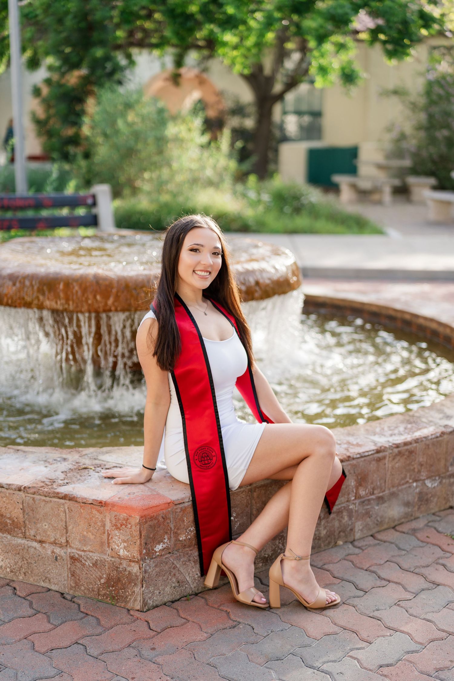 Portrait series by a decorative fountain with red accents and natural landscaping.