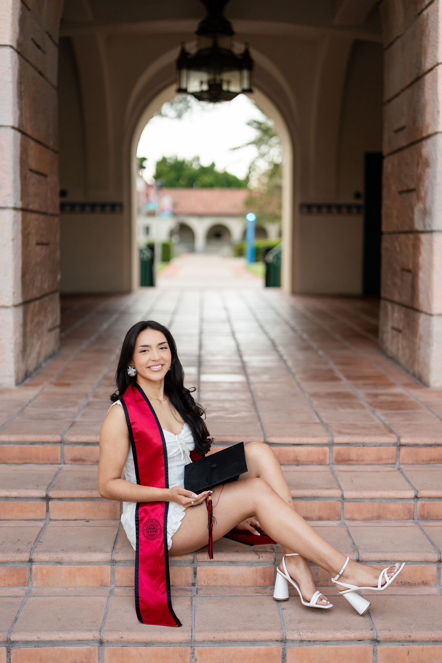 Graduation portraits taken in a Spanish-style archway with terracotta tiles and stone columns.