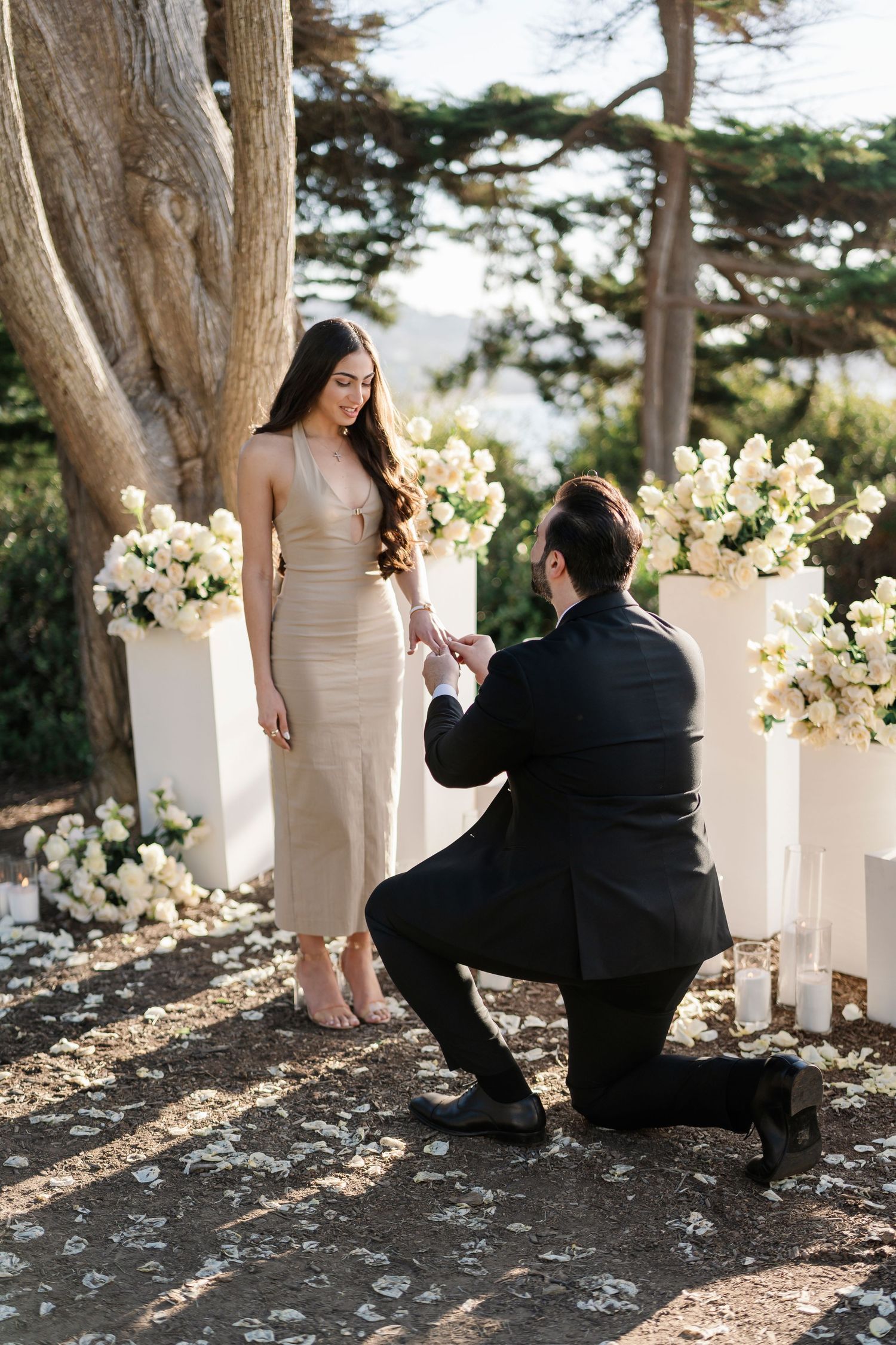 Intimate forest proposal moment surrounded by white floral pillars and natural scenery.