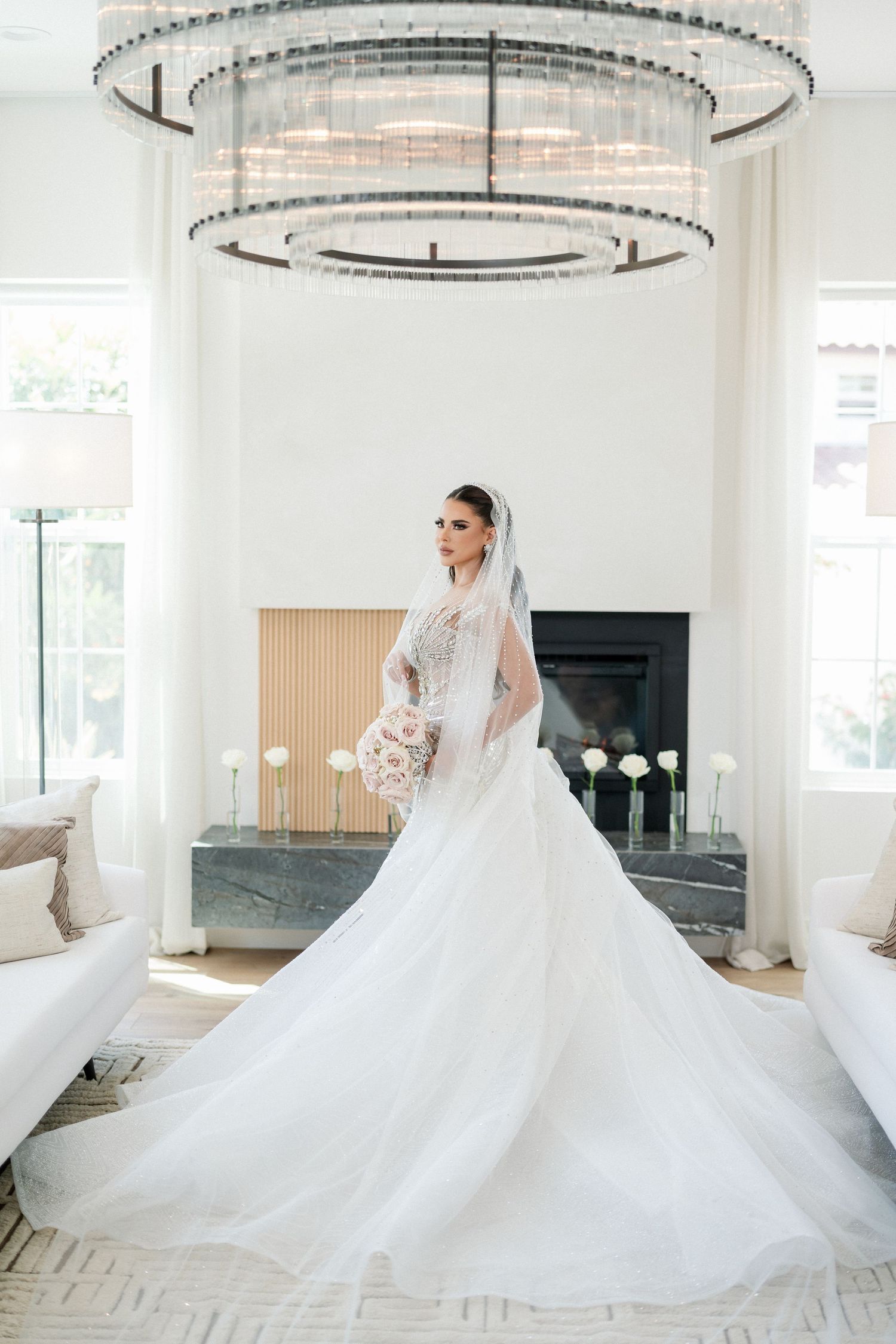 Dramatic bridal gown with flowing train captured in a modern white venue.
