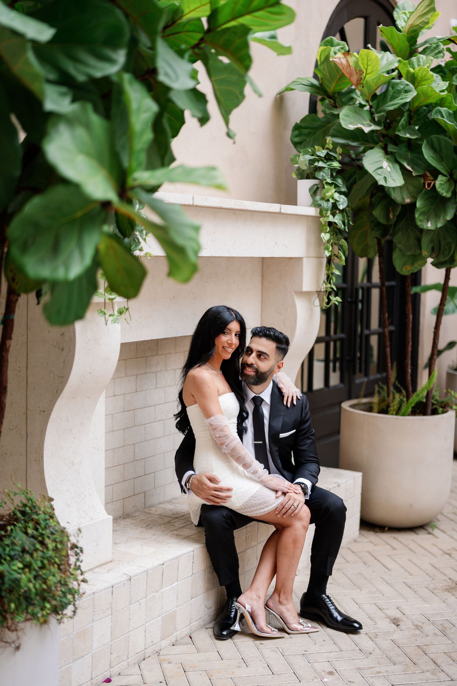 Intimate couple photos against beige walls with tropical plants and architectural details.