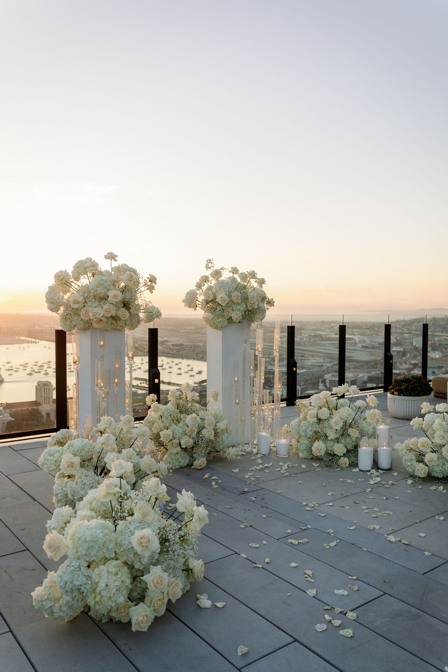 Modern white pillars adorned with white flowers line up against a sunset skyline.