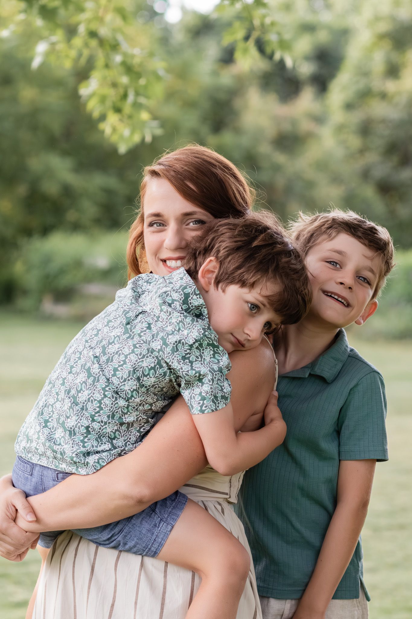 Mother with her two sons during a summer family photo session in a park.