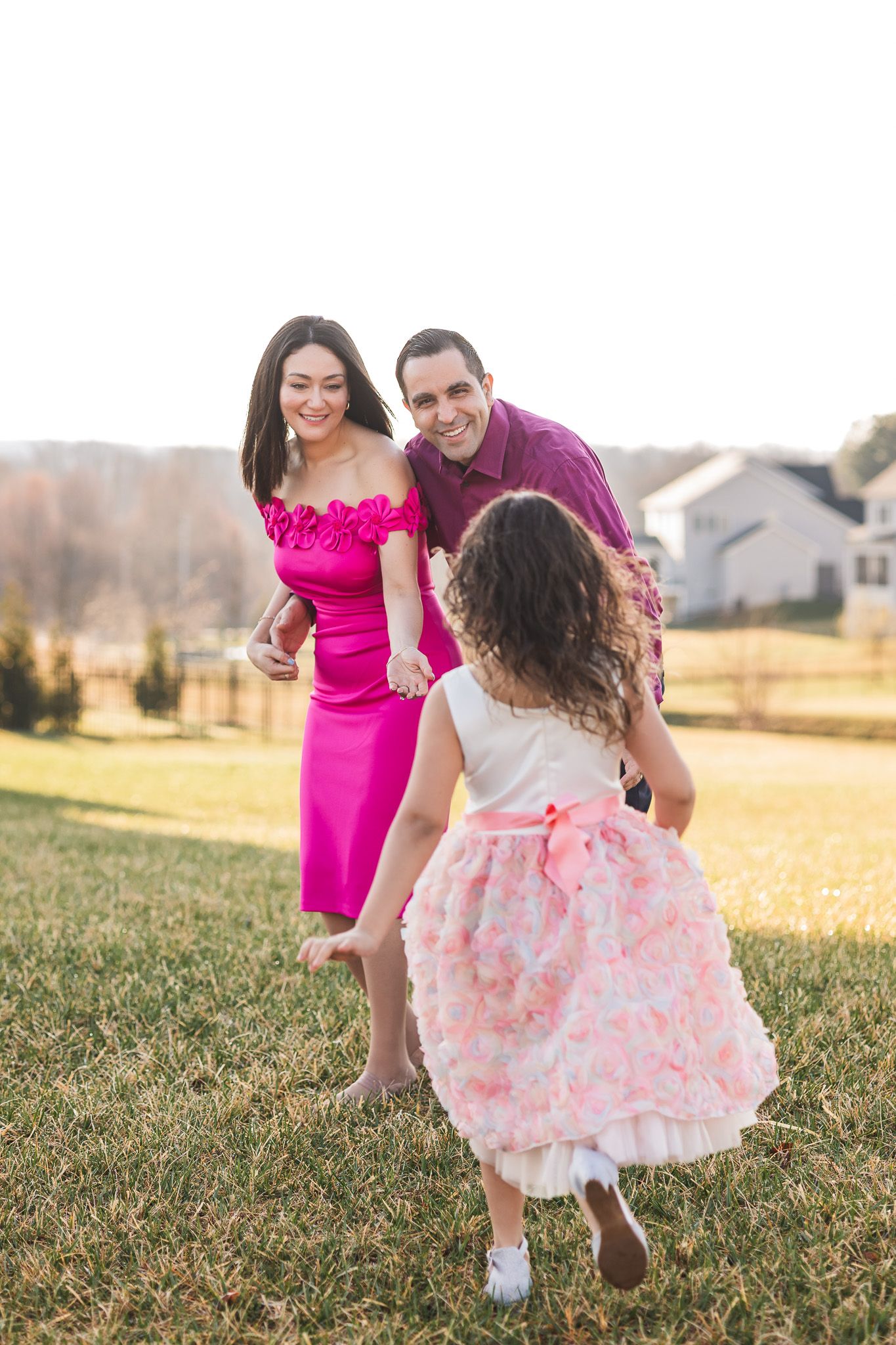Daughter running towards her parents during a morning photo session in a neighborhood.