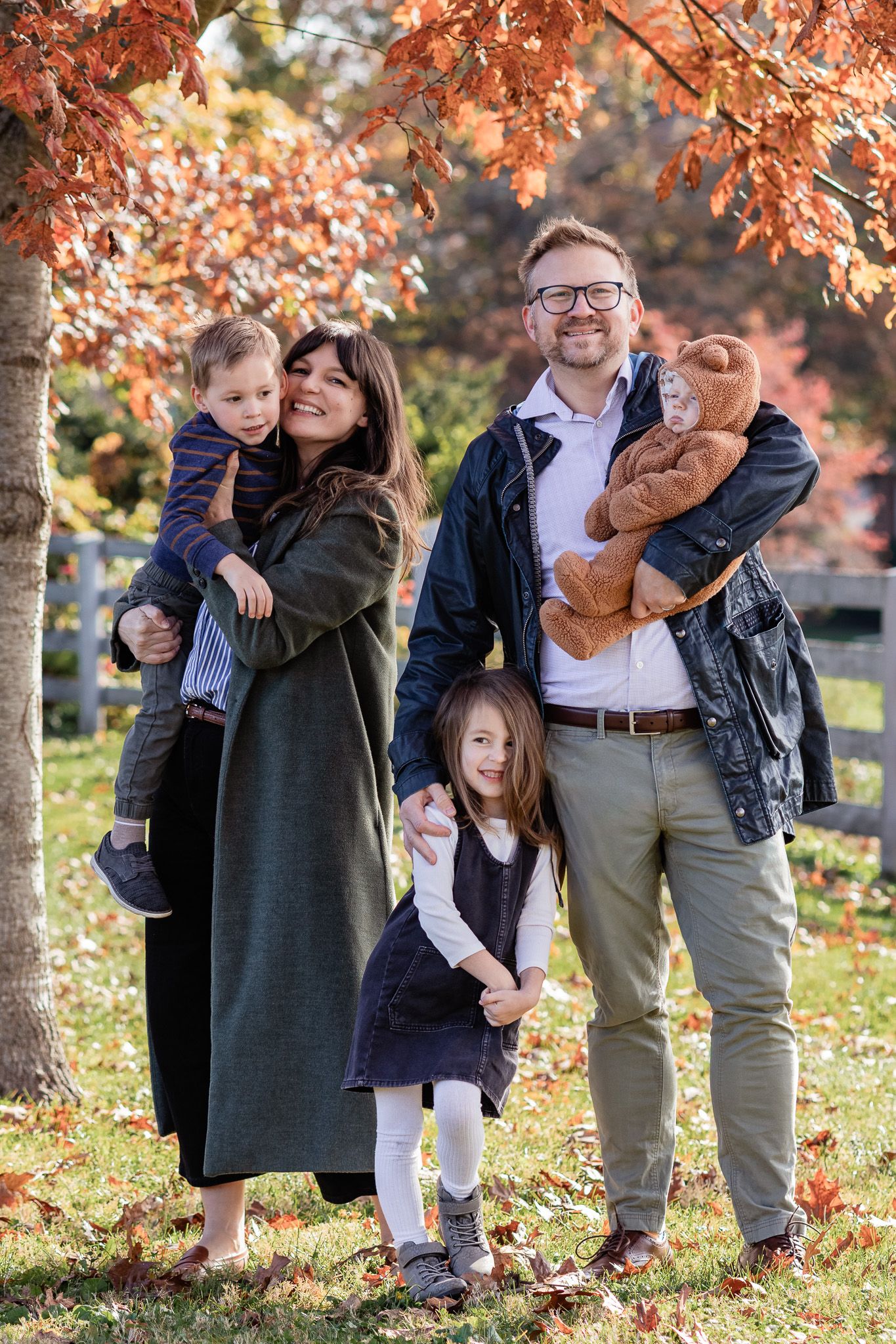 Family standing with orange autumn trees.