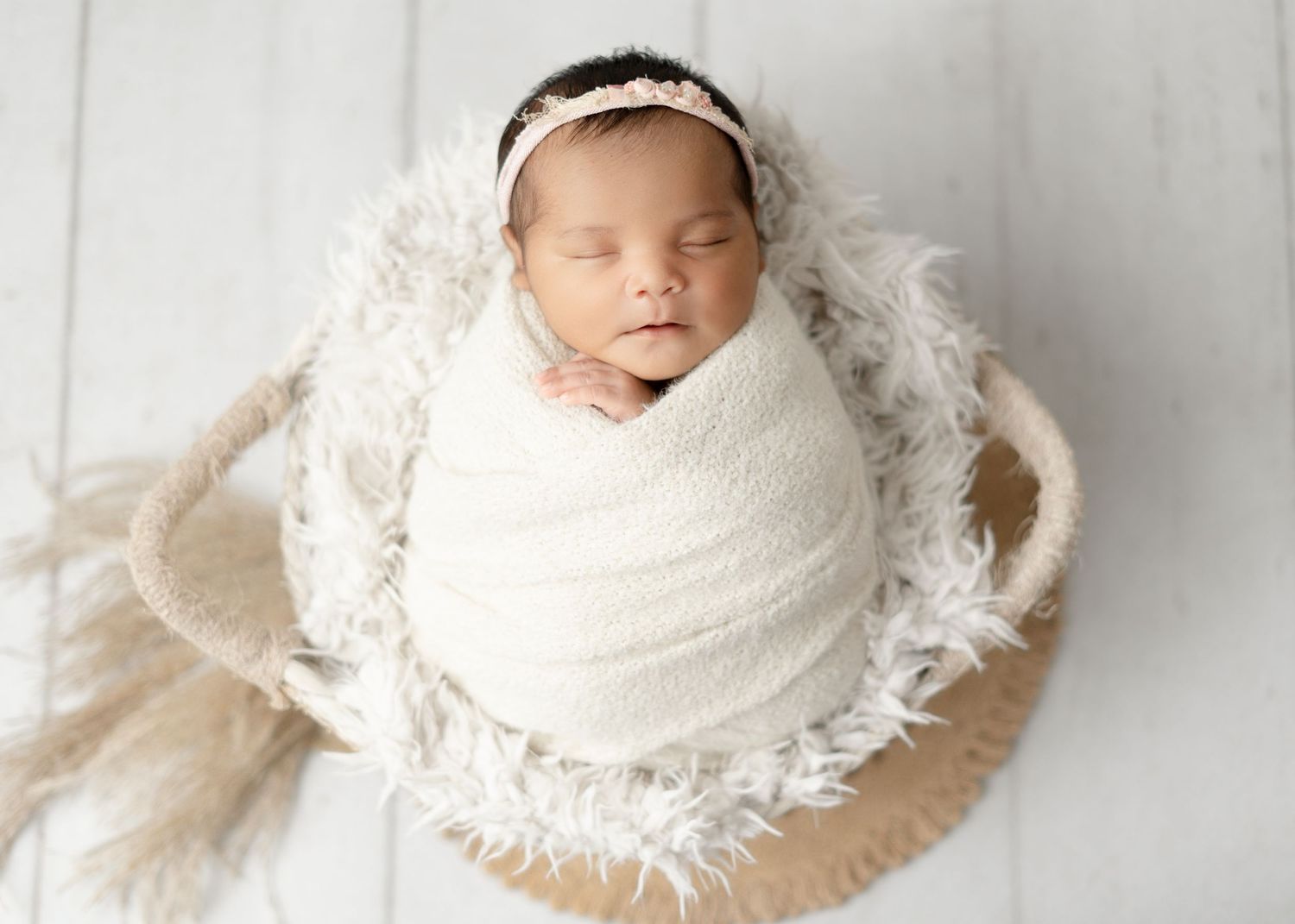 Newborn girl in a basket photoshoot, white colors for newborns. Boho newborn photography for newborn girls.
