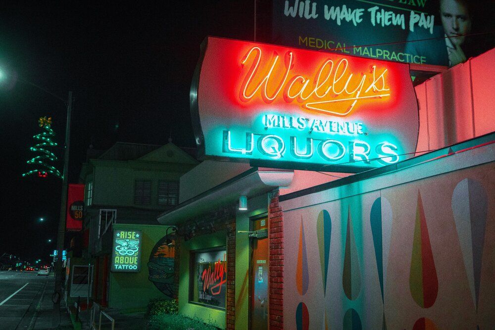 Vibrant neon signs glow in pink and turquoise hues against a dark urban nightscape.
