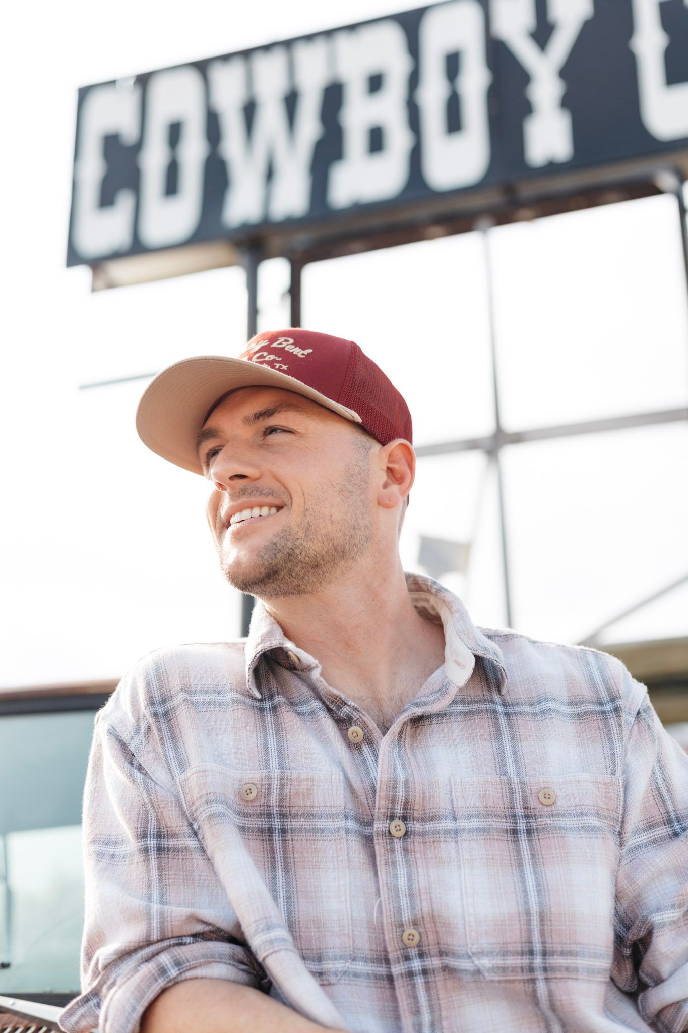 A person wearing a maroon baseball cap and plaid shirt is shown in a repeating sequence smiling and laughing.