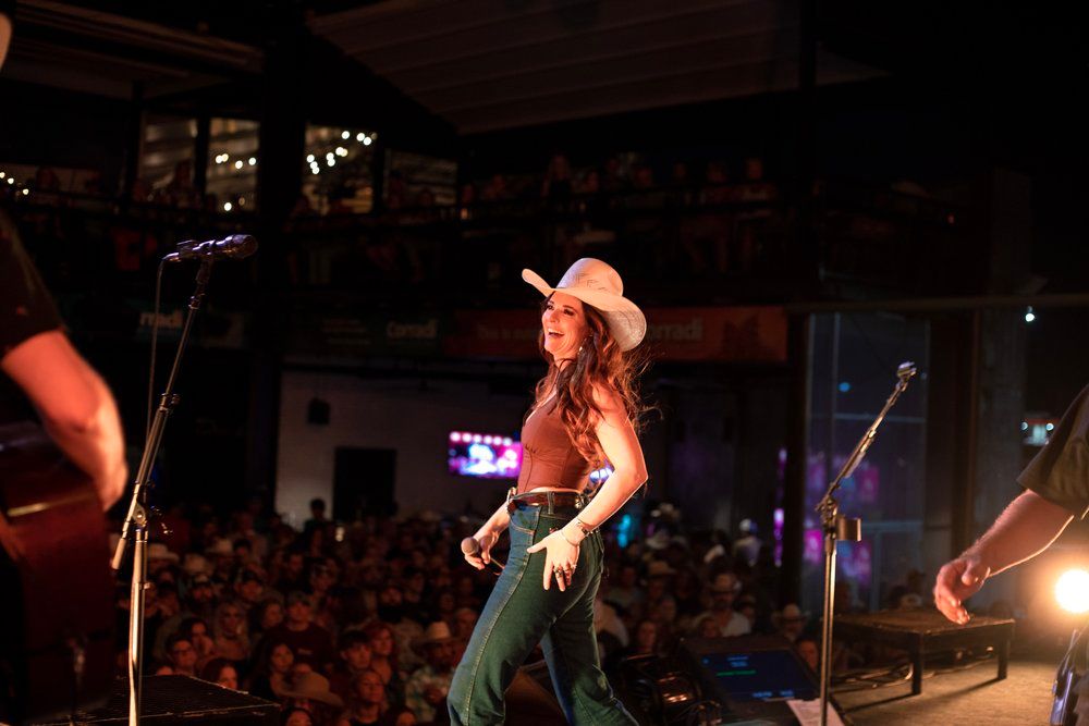 Country performer in cowboy hat dances on stage during concert performance.