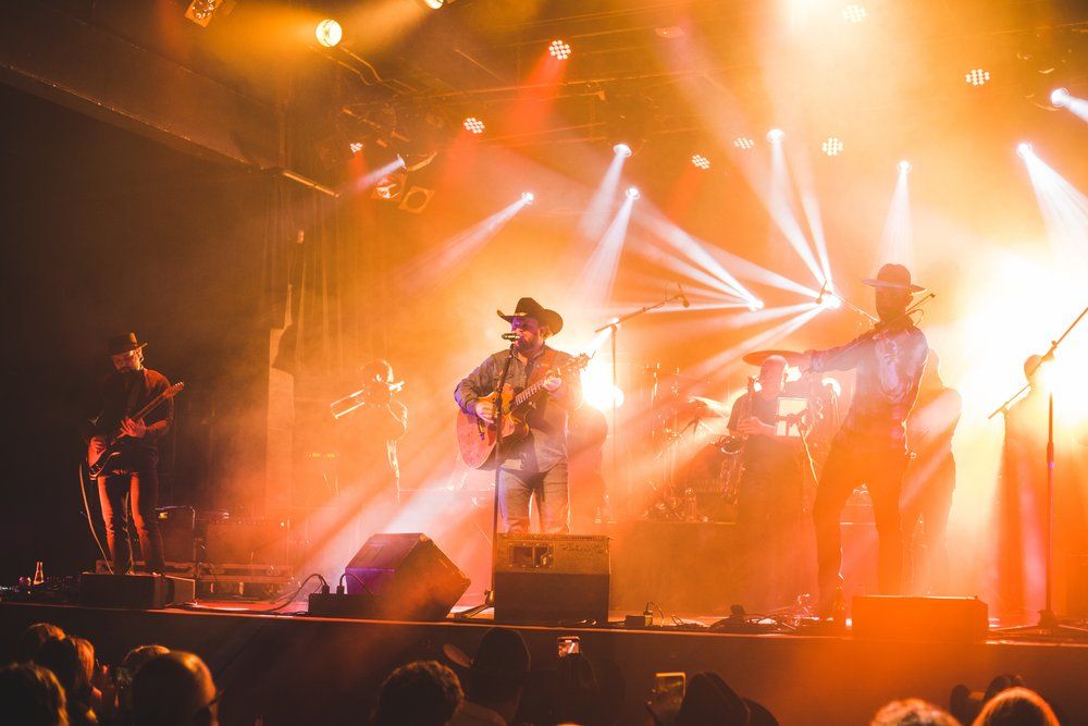 Country music concert with dramatic orange stage lighting and silhouetted performers.