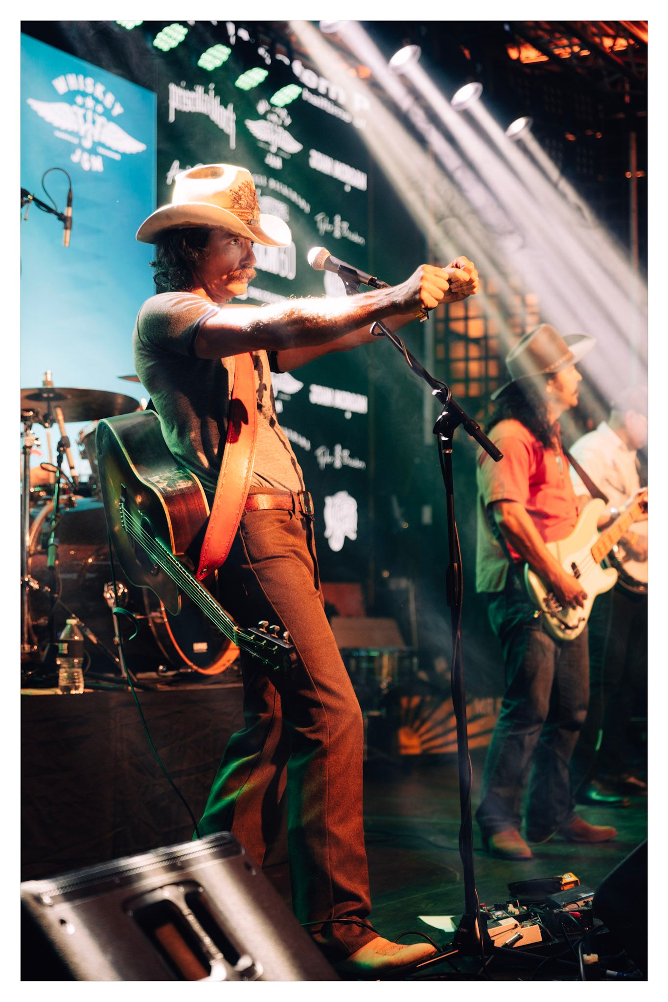 A performer plays guitar on stage under dramatic lighting during a live concert performance.