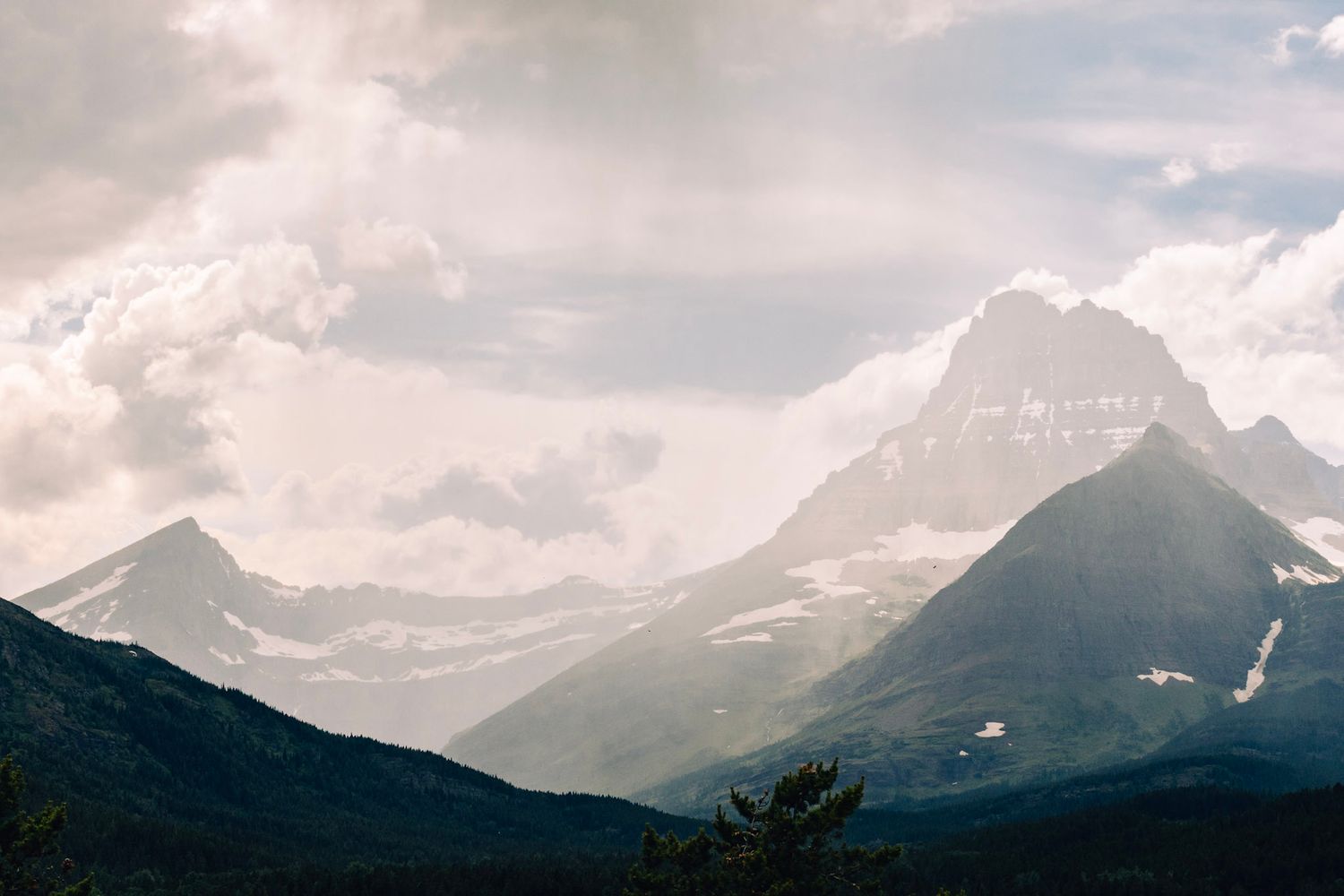 A dramatic panoramic view of mountain peaks silhouetted against moody clouds at sunset in the Canadian Rockies.