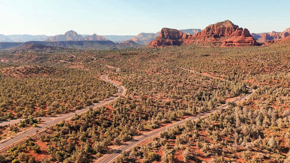 Aerial view of desert landscape with winding road through red rock formations in Arizona.
