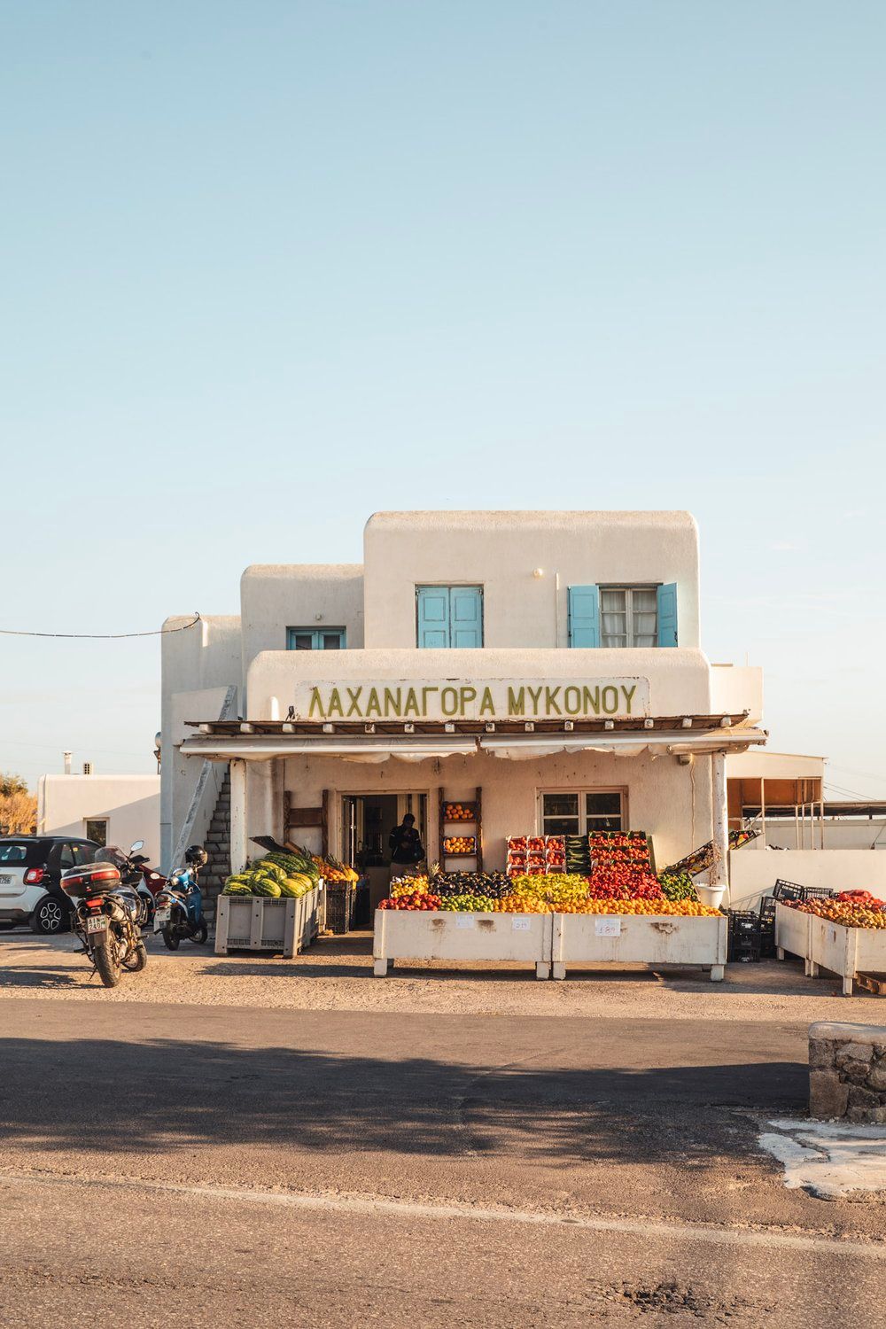 White Mediterranean storefront with fresh produce displays and Greek signage.