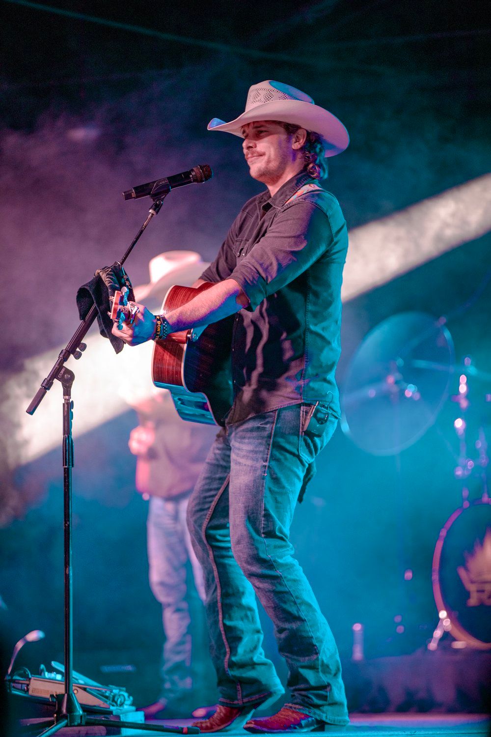 CountryRandall King musician in cowboy hat playing acoustic guitar on stage with blue and teal lighting.