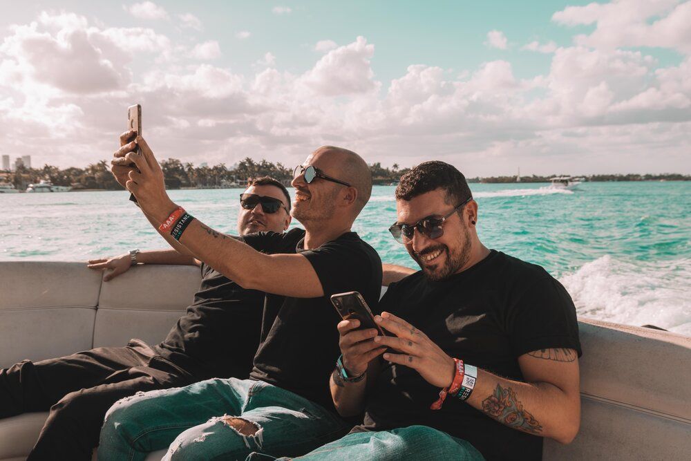Group enjoying a summer day on a boat while cruising along tropical waters beneath a bright blue sky.