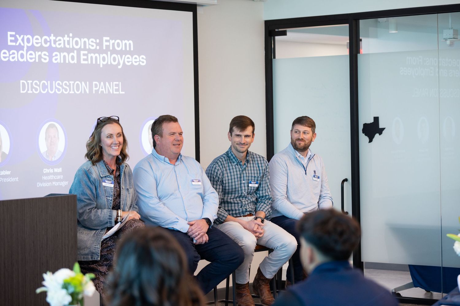 Four panelists seated at a discussion panel on leader and employee expectations at a corporate event.