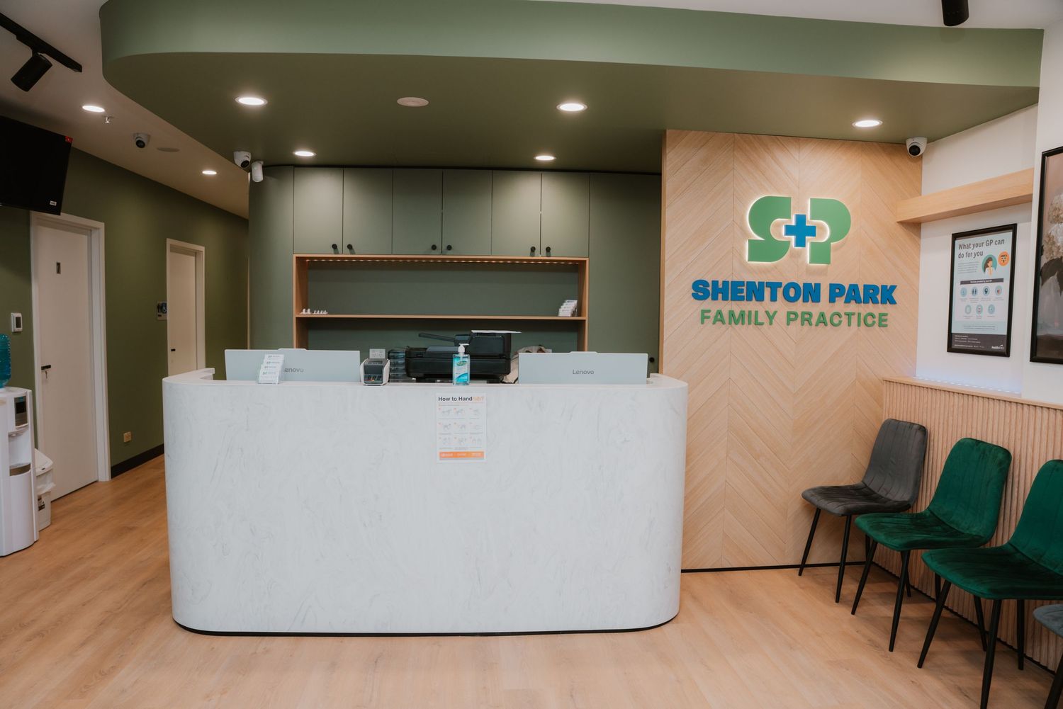 Modern medical reception desk at Shenton Park Family Practice with green chairs.