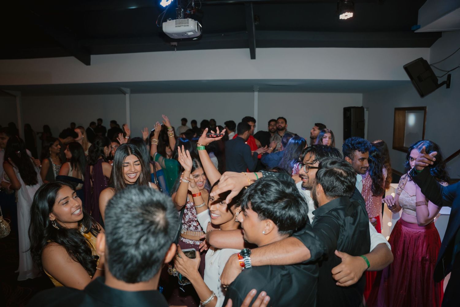 Lively Indian wedding reception dance floor packed with guests celebrating in colorful formal attire.
