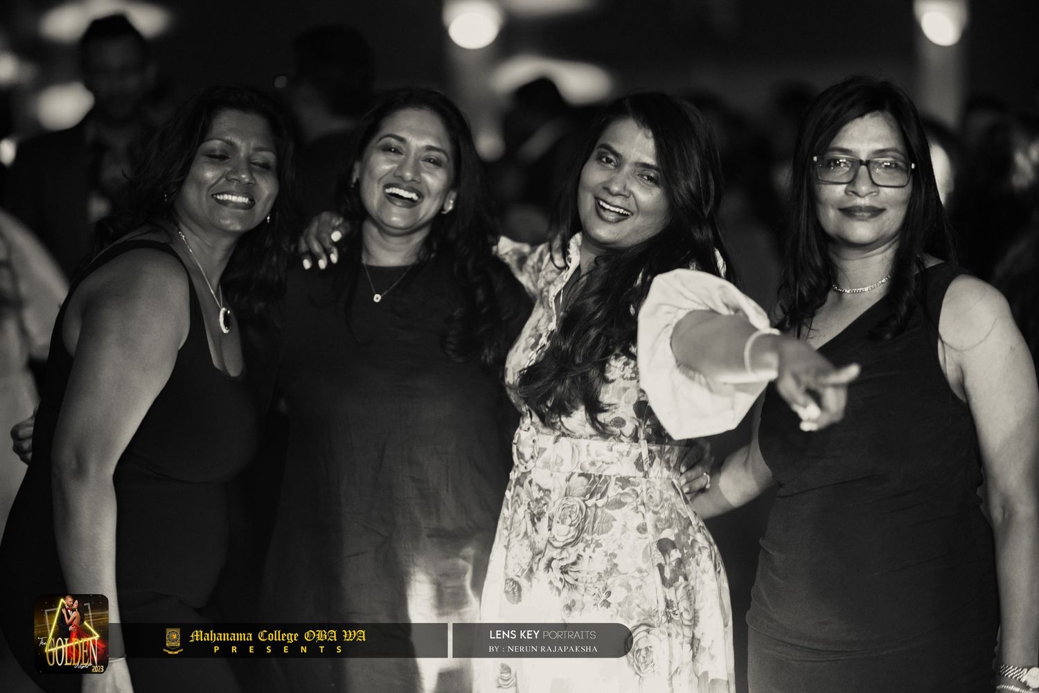 Four women smiling and posing together at a nighttime outdoor event in black and white photo.
