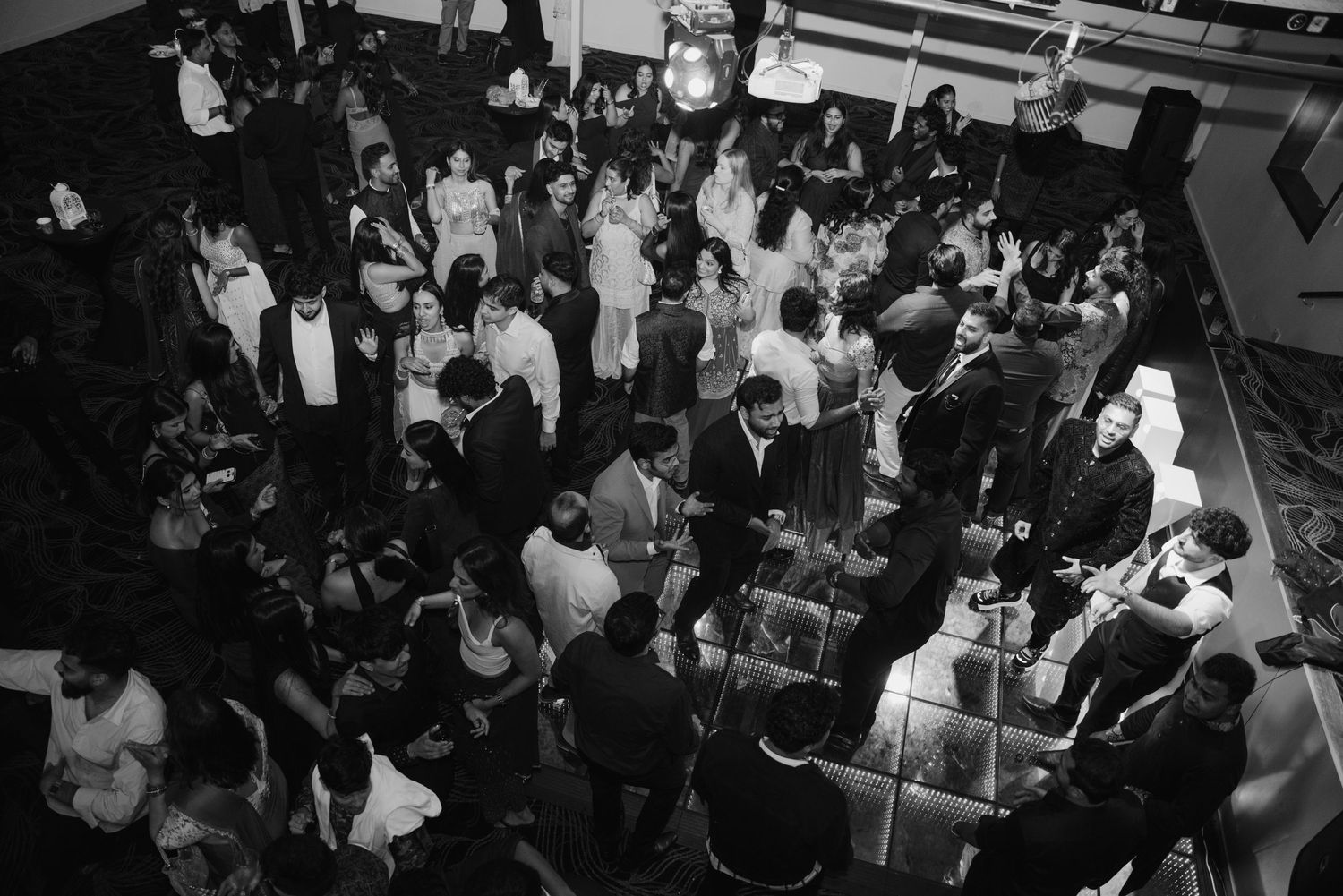Black and white aerial view of elegant wedding reception ballroom filled with dancing guests.
