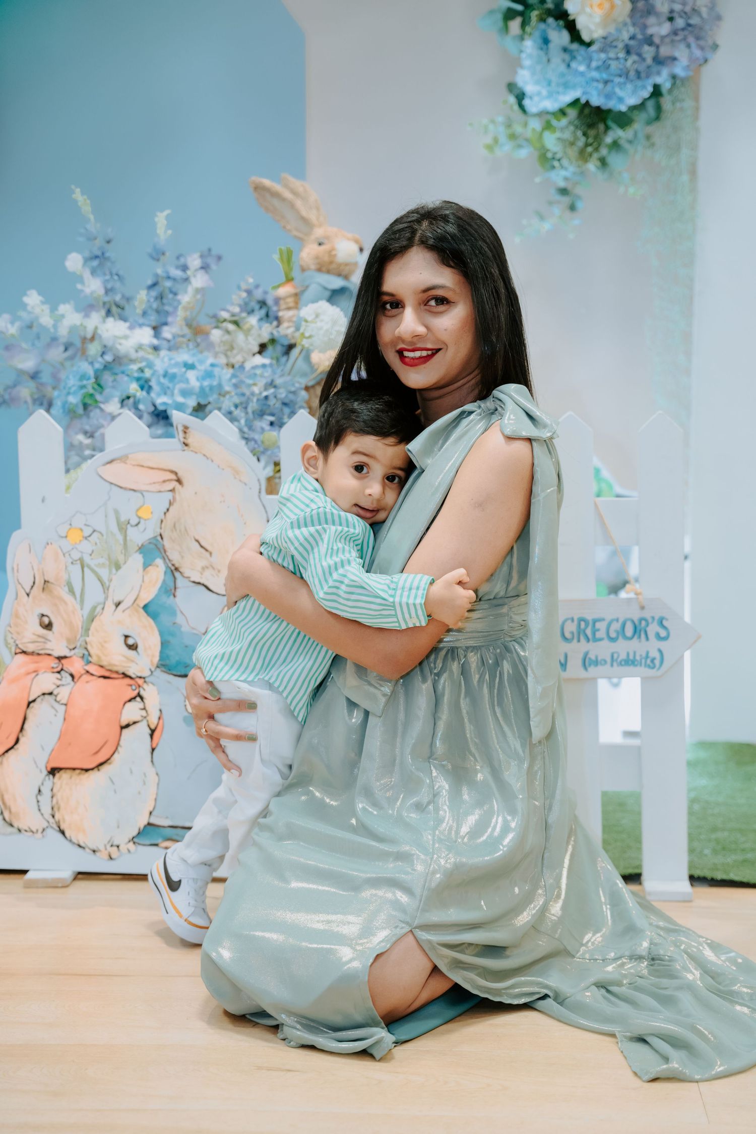 Mother in mint dress hugging toddler son at Peter Rabbit themed first birthday party.