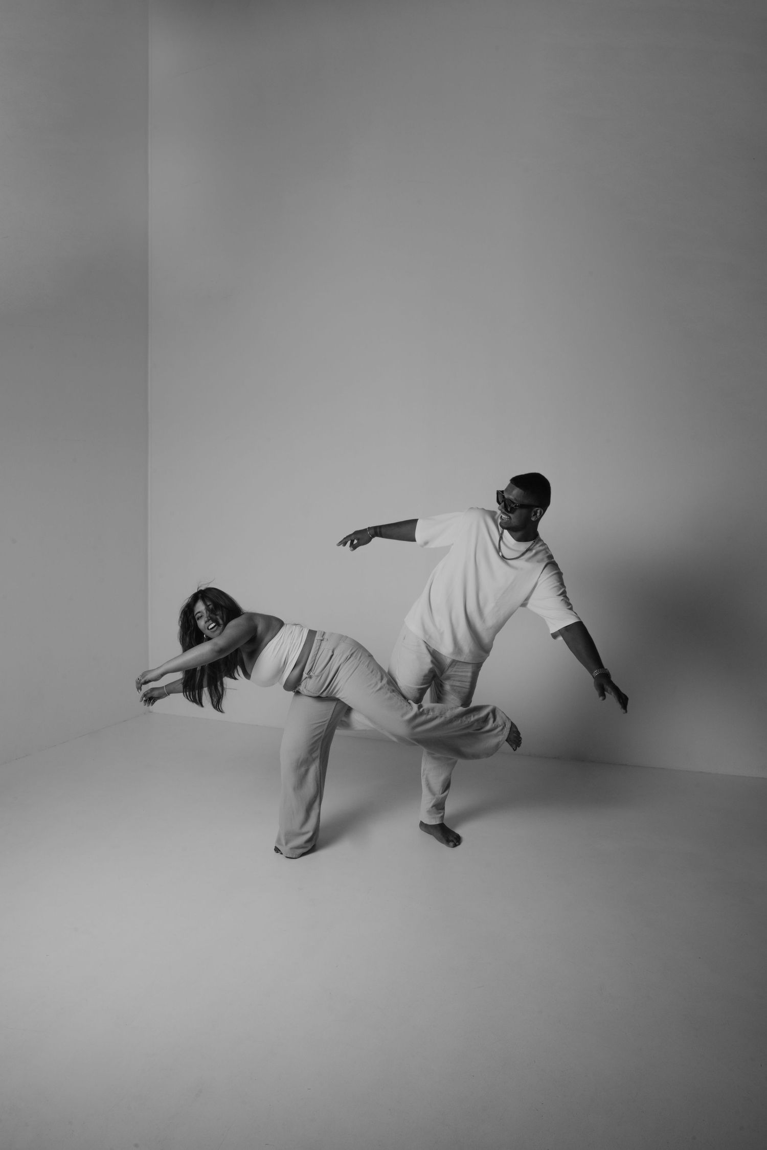 A black and white photo of two dancers performing a dramatic contemporary dance routine in a studio space.