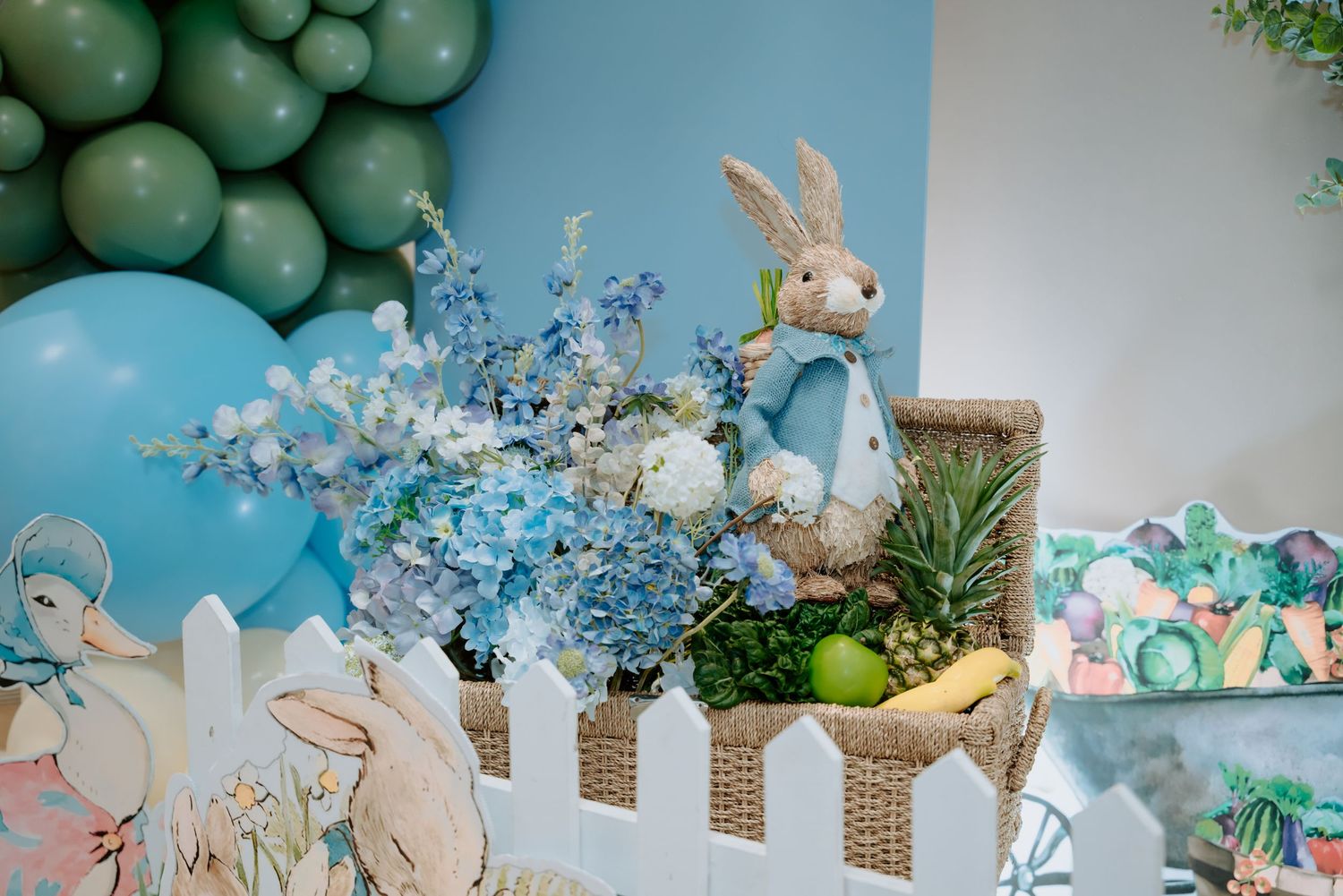 Peter Rabbit themed first birthday party decoration with blue hydrangeas and bunny figurine.