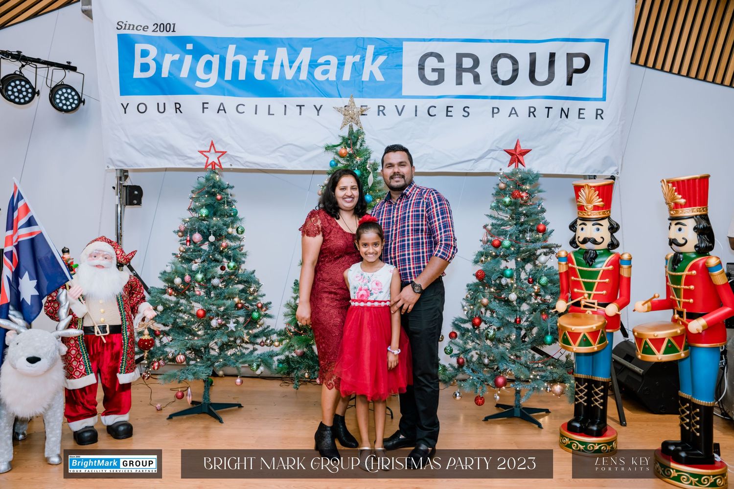 A family of three posing in front of Christmas decorations at BrightMark Group Christmas Party 2023.