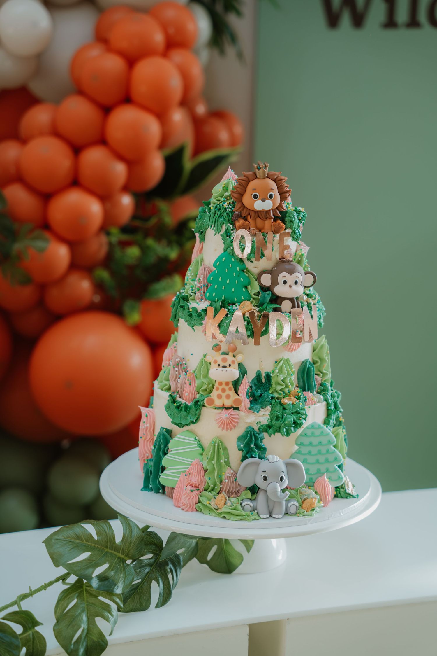 Safari-themed first birthday cake with jungle animals including lion, giraffe, monkey, and elephant decorations.
