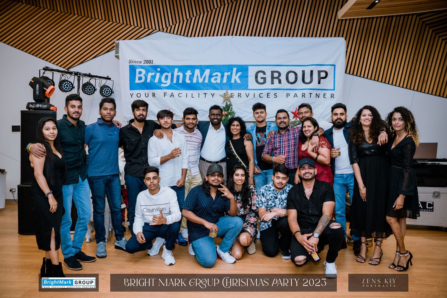 Large group photo of attendees at BrightMark Group Christmas Party 2023 in front of company banner.