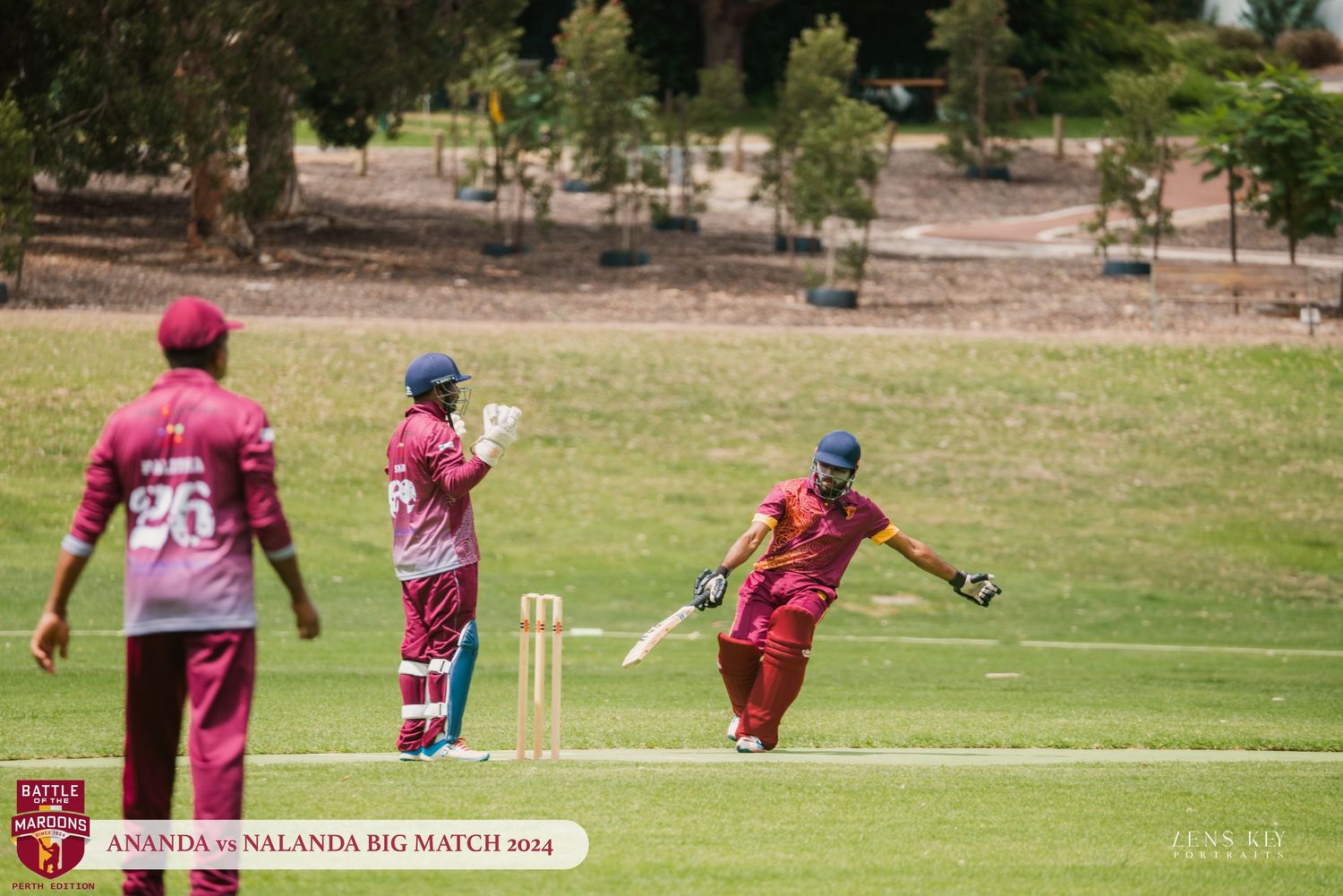 Cricket players in maroon uniforms playing during Ananda vs Nalanda Big Match 2014 on a sunny day.