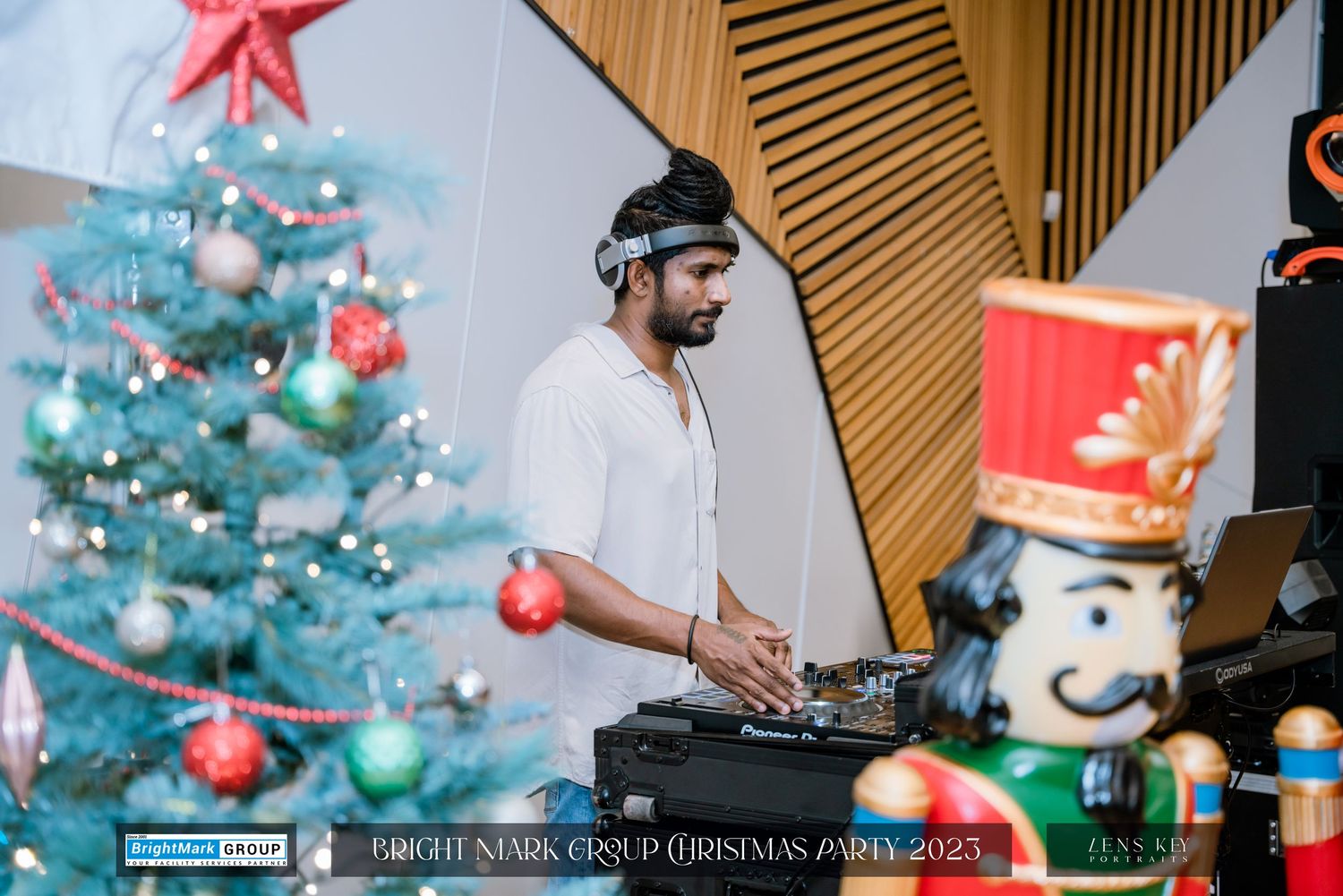 A DJ performing next to a decorated Christmas tree at BrightMark Group Christmas Party 2023.