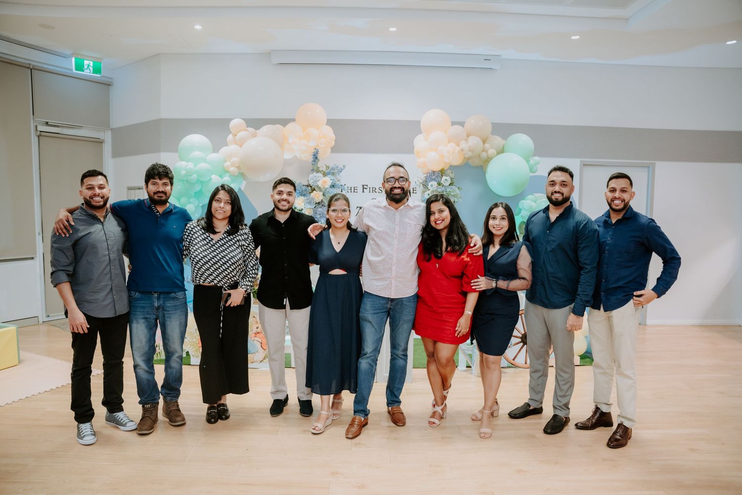 Group of ten adults pose together at Peter Rabbit themed first birthday party celebration.