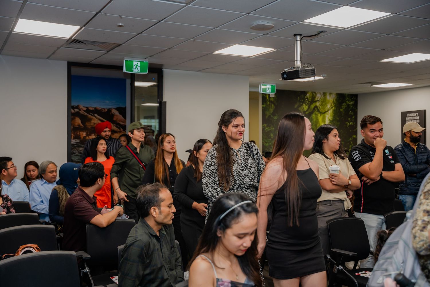 Guests mingling and standing in a conference room during a college event or ceremony.