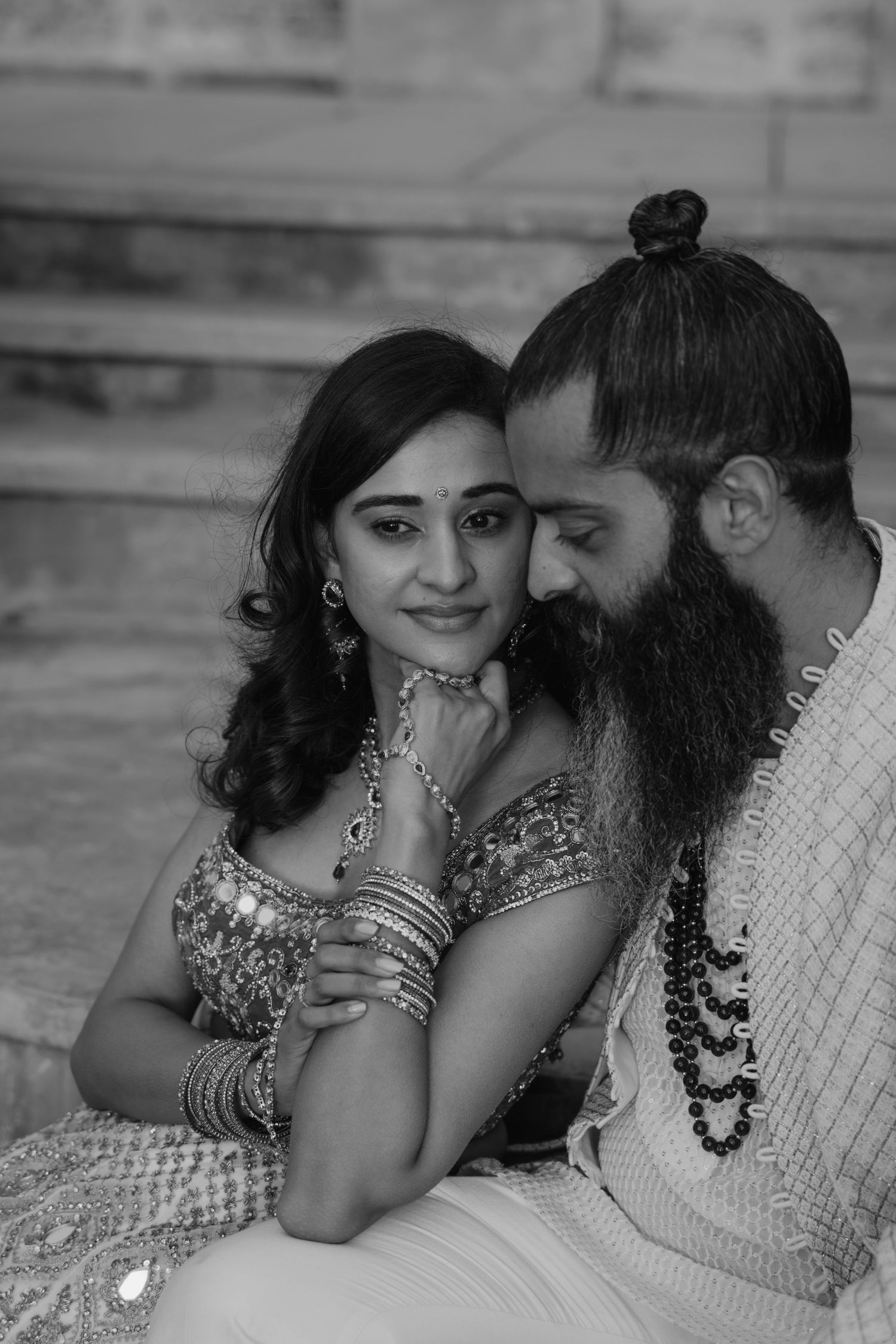 Black and white intimate portrait of Indian bride and bearded groom sharing a tender moment.