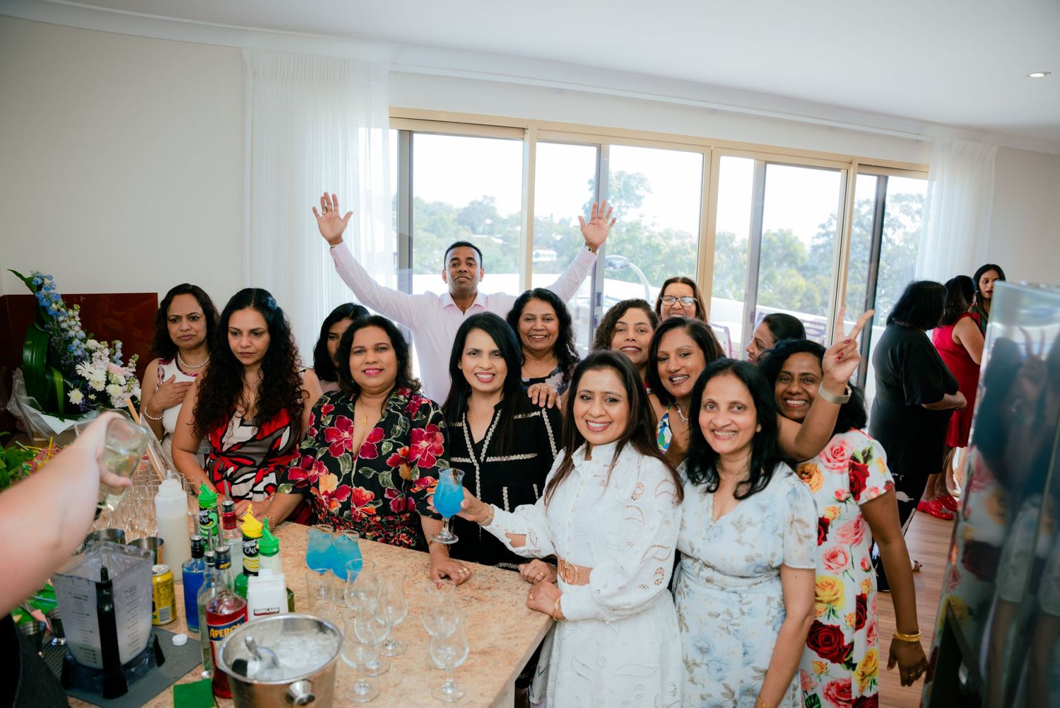 Large group of women smile and celebrate together at a festive indoor birthday party gathering.